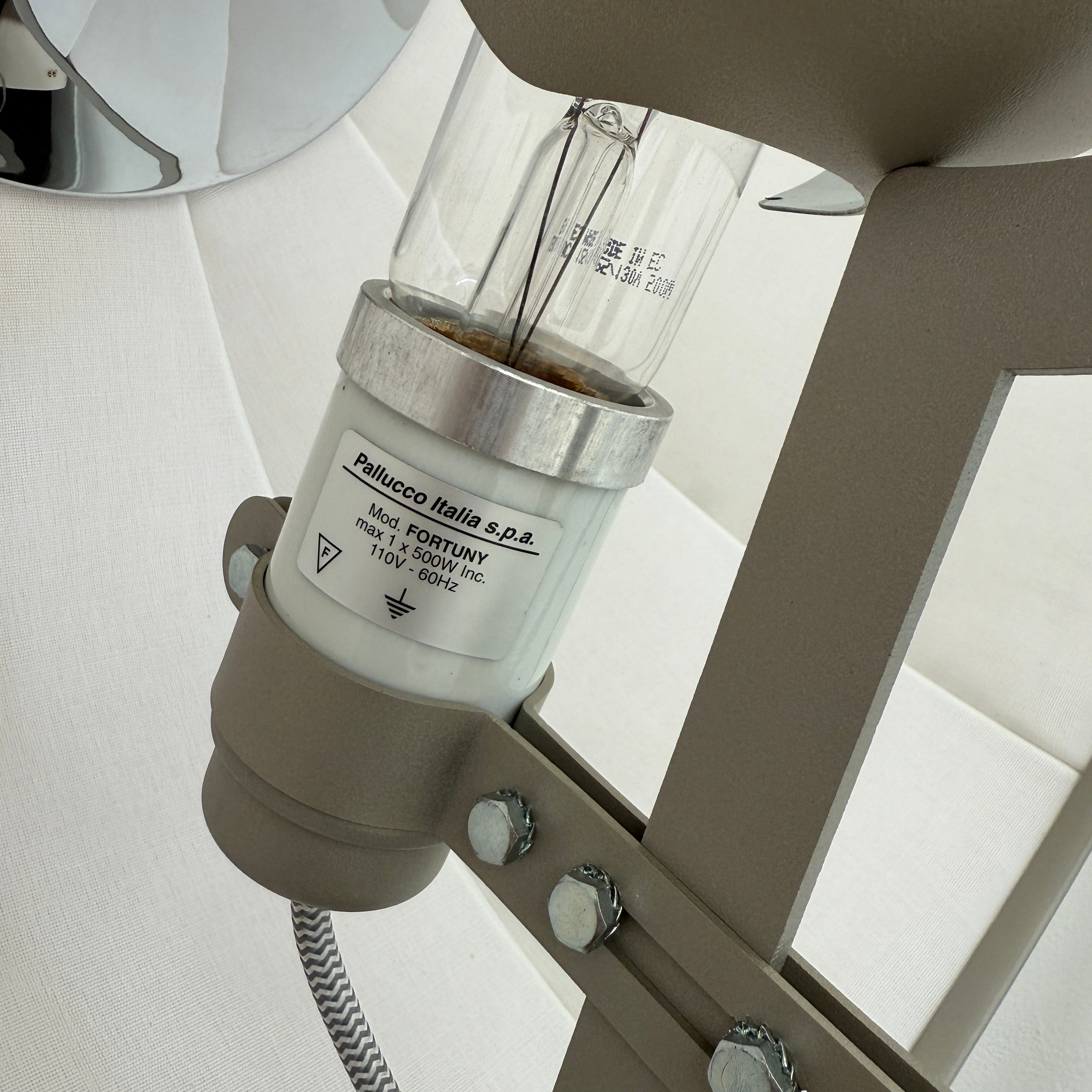 The Pallucco Italia Fortuny Ornament Floor Lamp, with its visible bulb and patterned spherical shade, gracefully stands on a plain white background, epitomizing the elegance of Pallucco Italia.