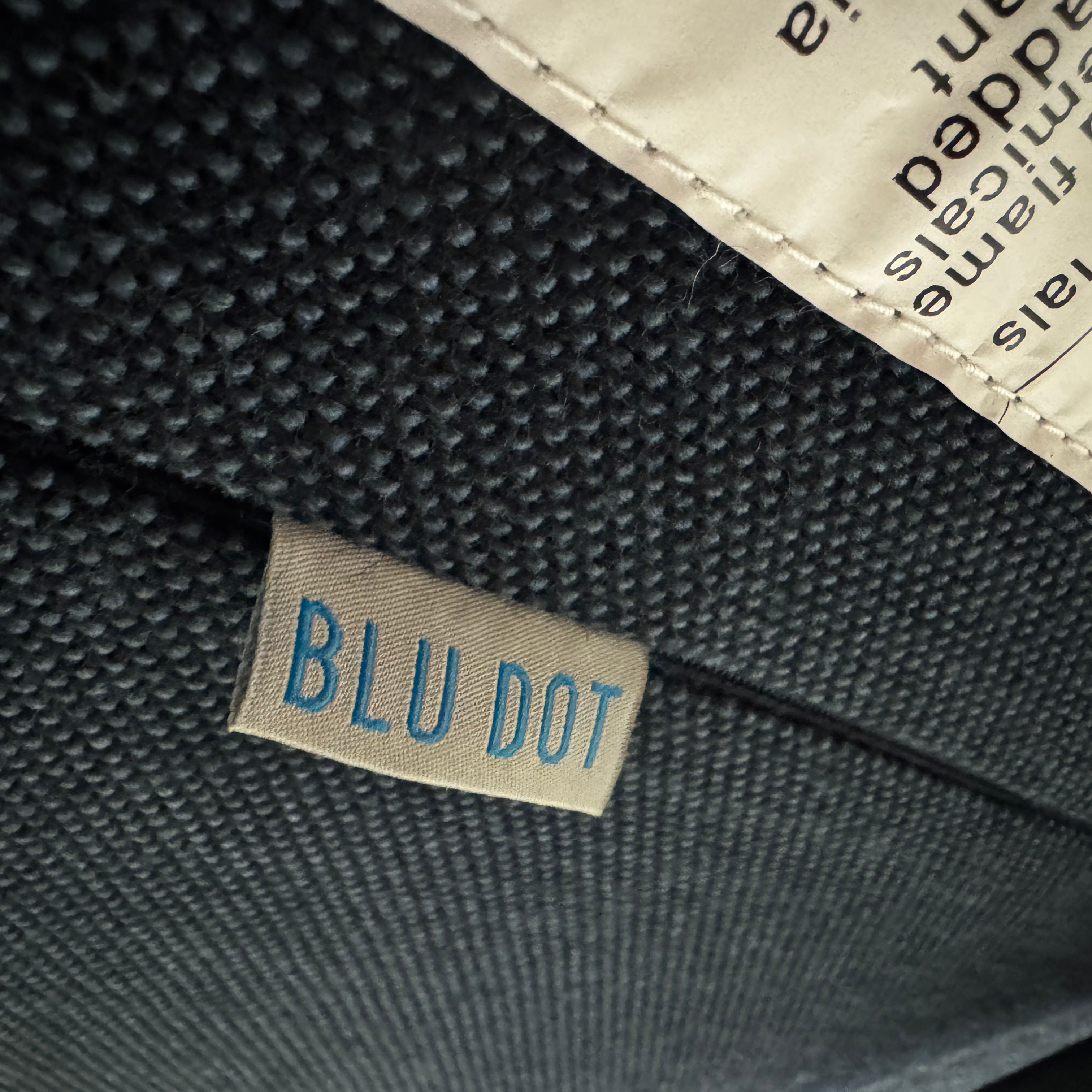 The Blu Dot Field Chair & Ottoman by Blu Dot features a modern dark grey design with black metal legs and contemporary details, showcased against a plain white background.