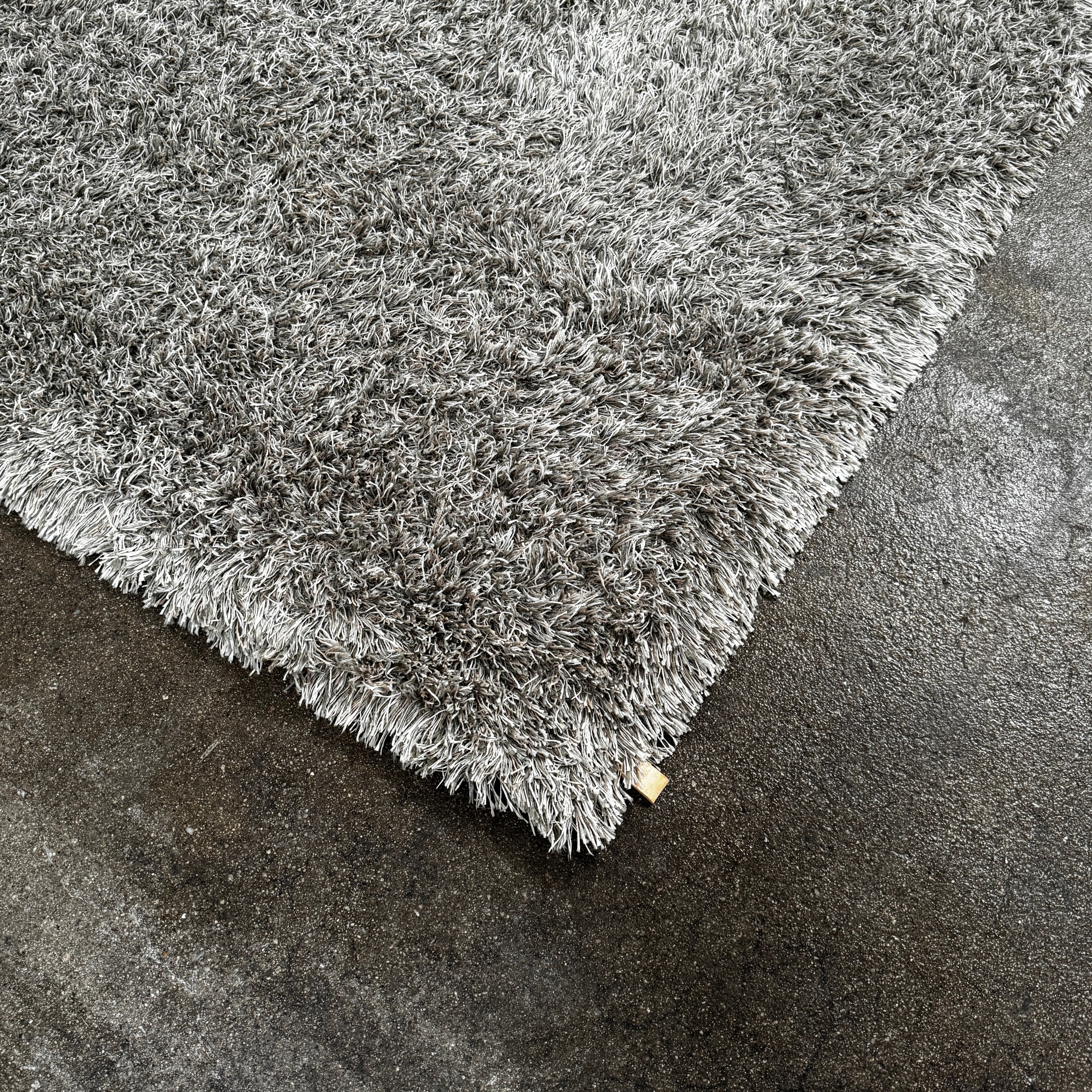 A close-up of the corner of a Kasthall Gray Fogg 2 Shag Rug (7 x 10) is shown on a white background.