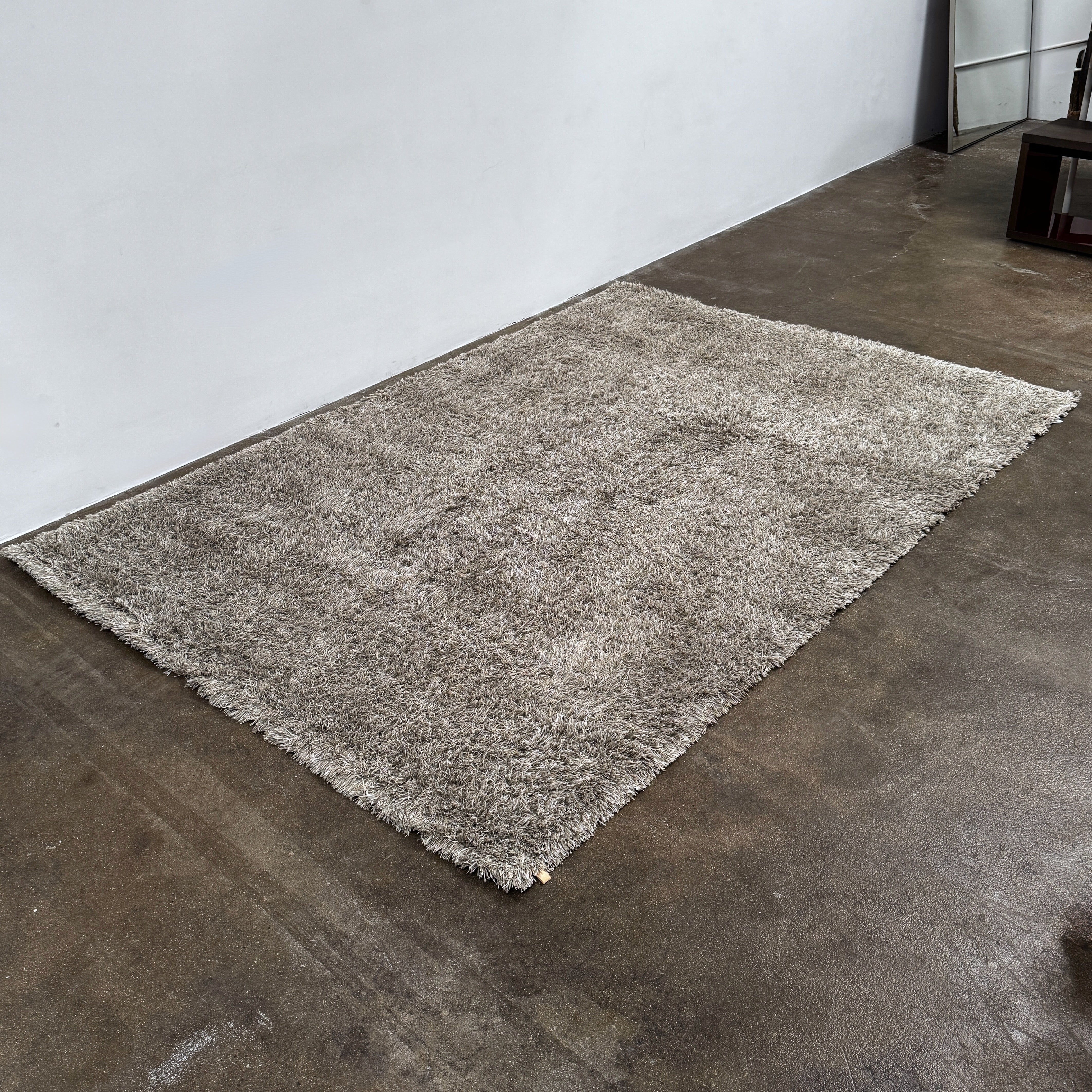 A close-up of the corner of a Kasthall Gray Fogg 2 Shag Rug (7 x 10) is shown on a white background.