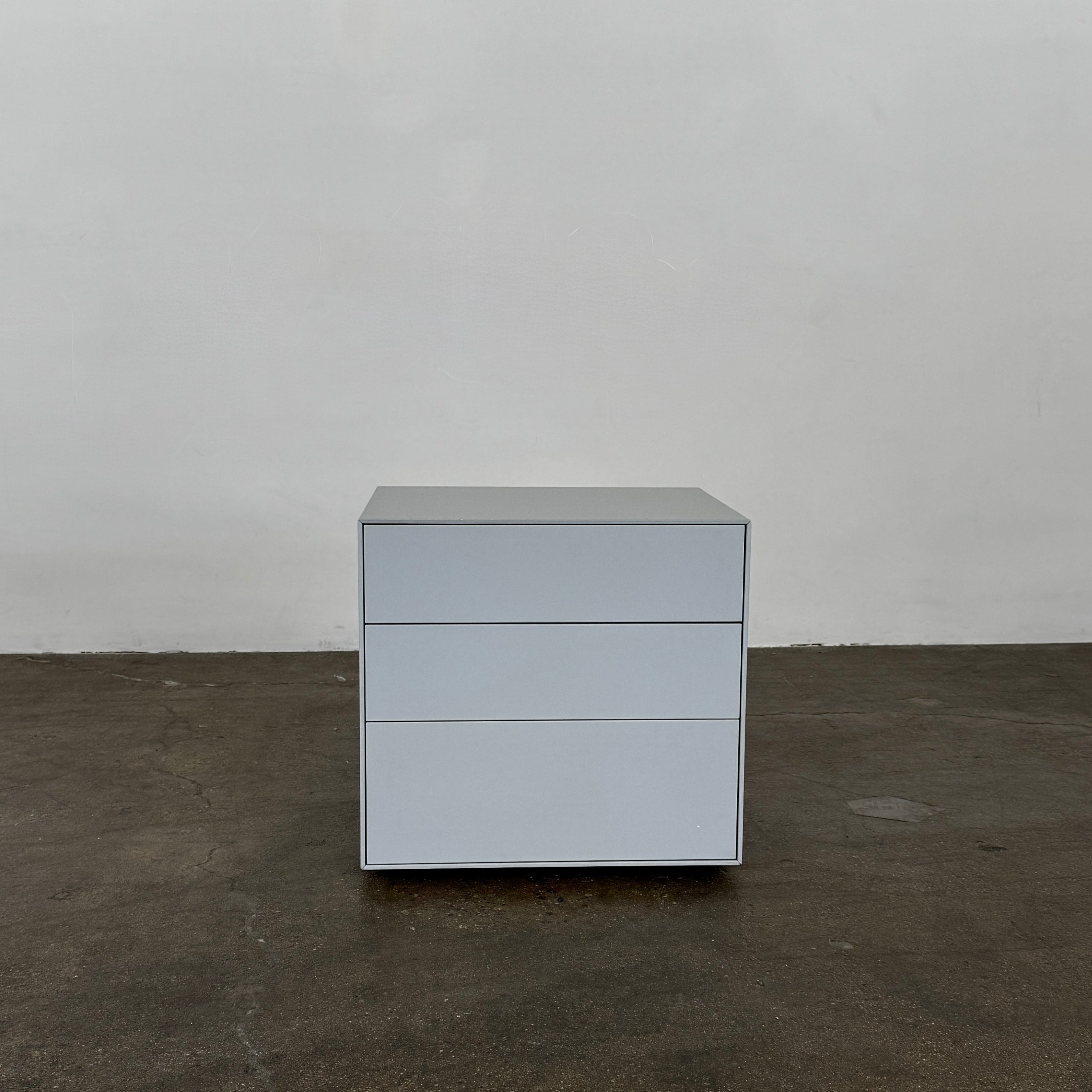 The Treku Lauki collection Side Table (2) by Treku, a gray rectangular side table with three drawers and a minimalist design, is shown against a plain white background.
