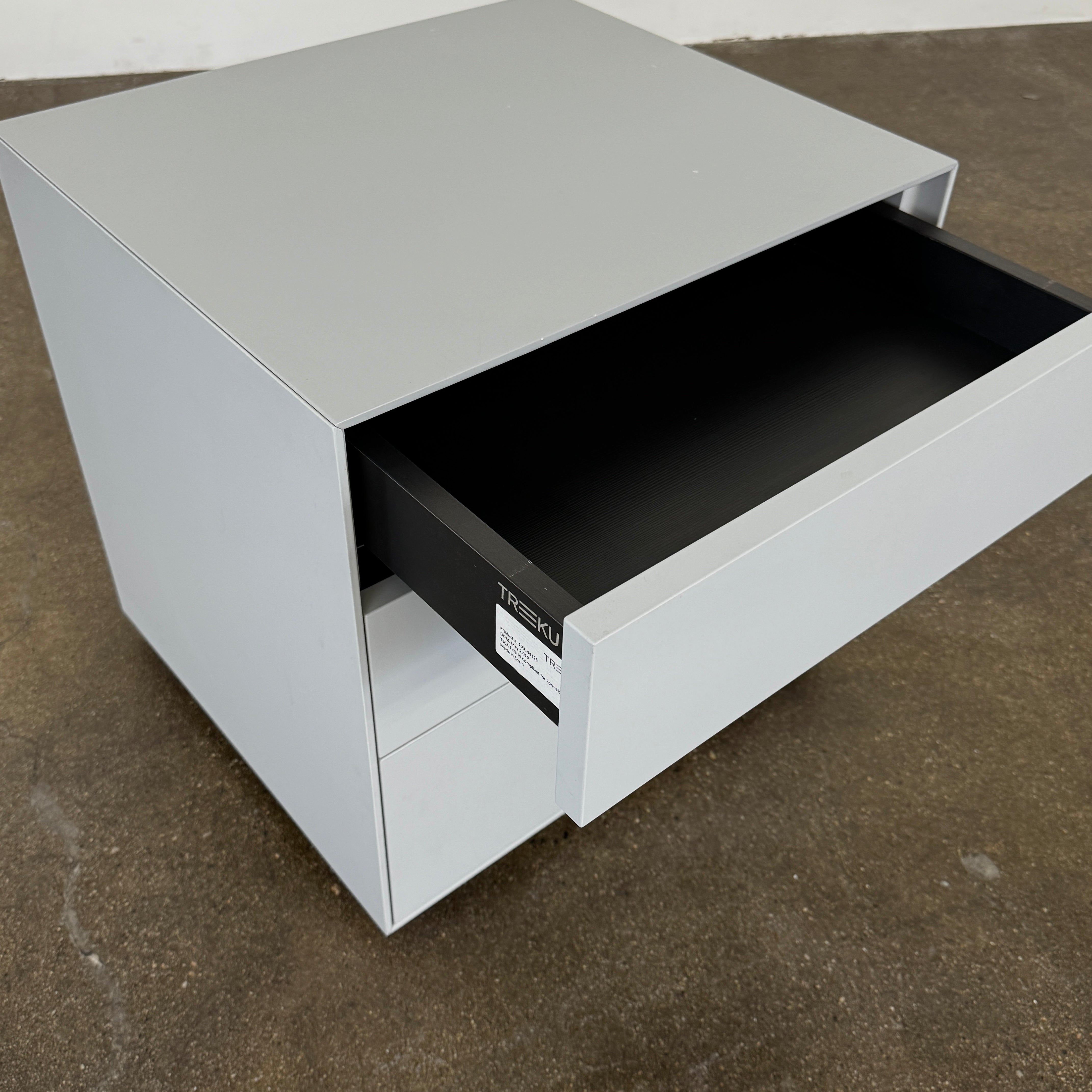 The Treku Lauki collection Side Table (2) by Treku, a gray rectangular side table with three drawers and a minimalist design, is shown against a plain white background.
