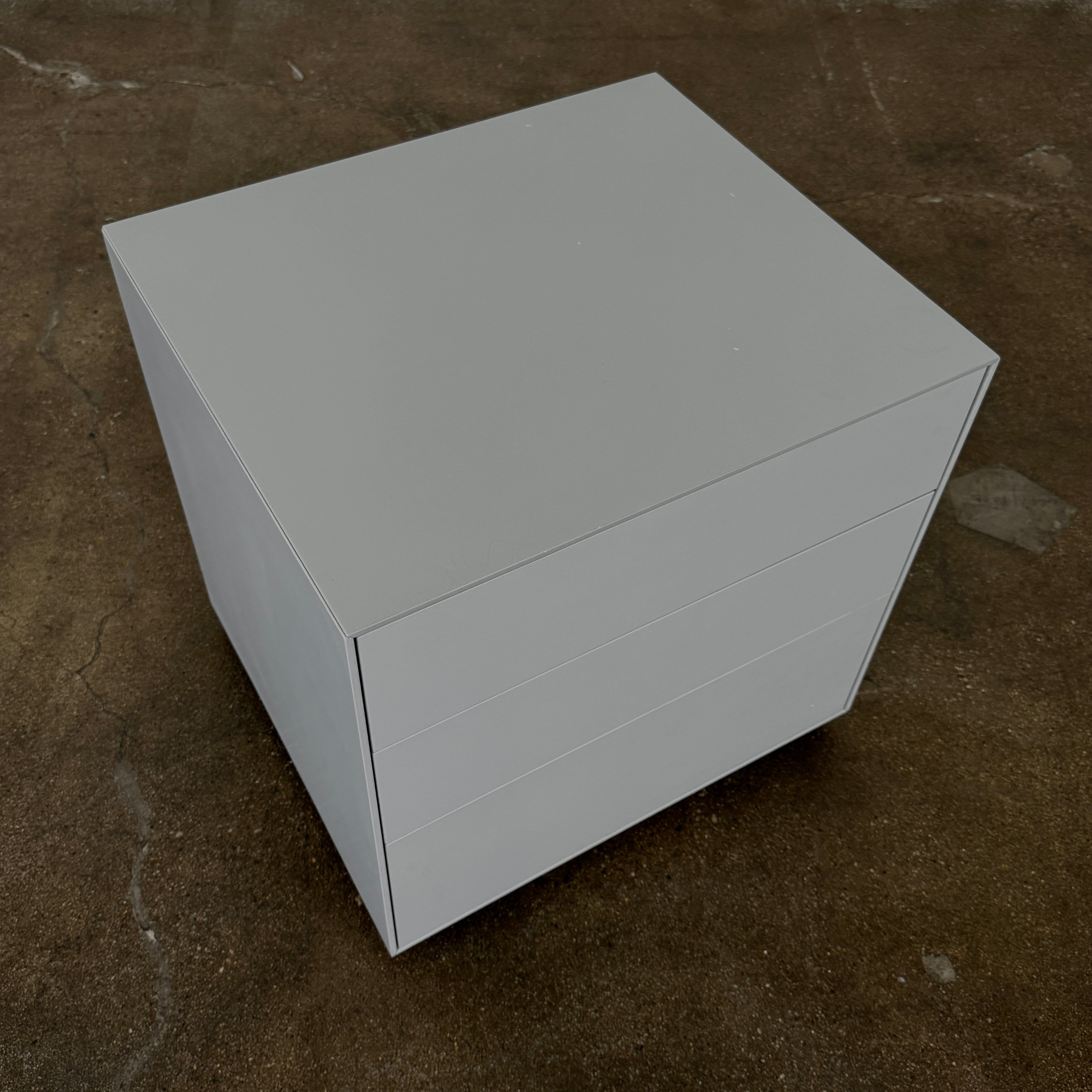 The Treku Lauki collection Side Table (2) by Treku, a gray rectangular side table with three drawers and a minimalist design, is shown against a plain white background.