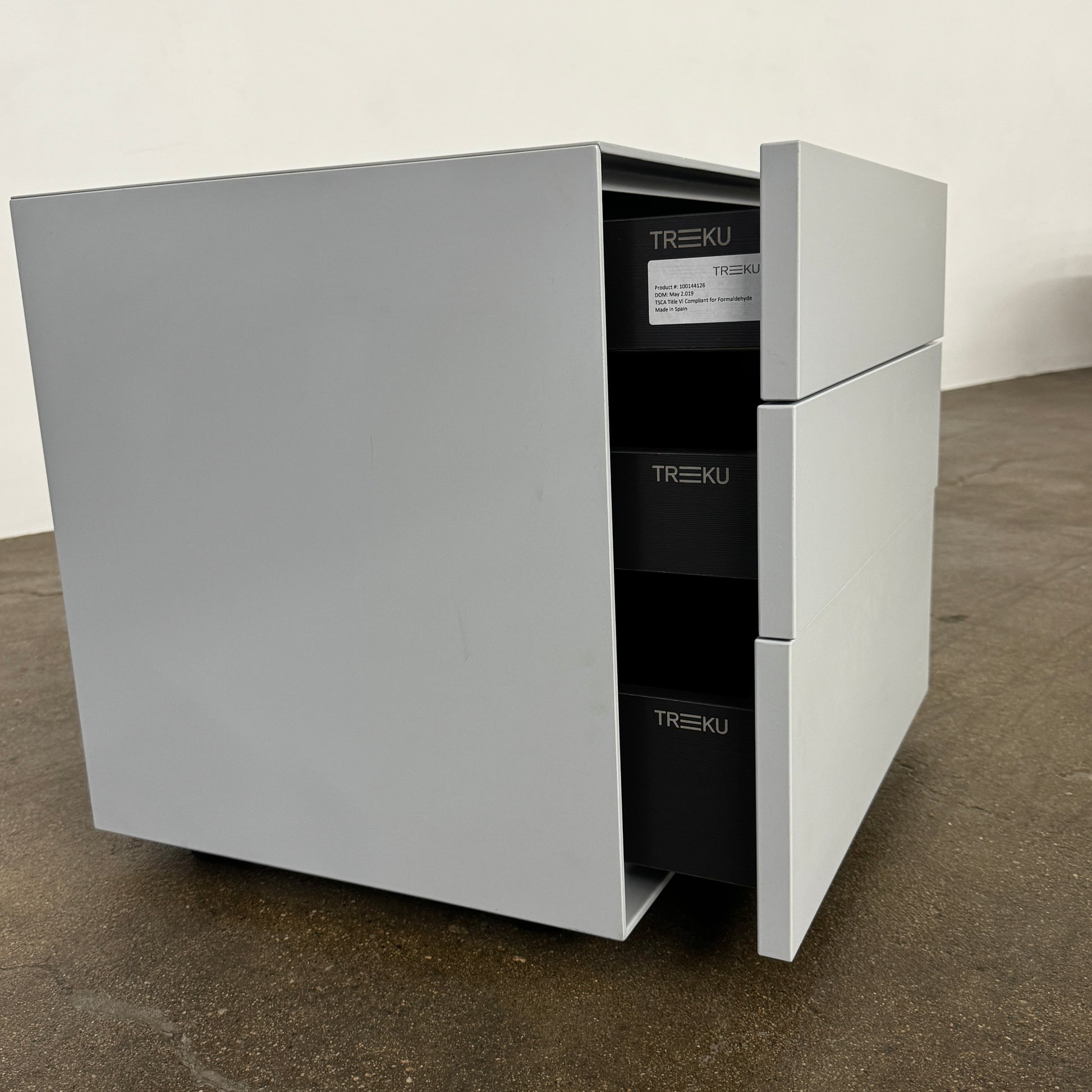 The Treku Lauki collection Side Table (2) by Treku, a gray rectangular side table with three drawers and a minimalist design, is shown against a plain white background.