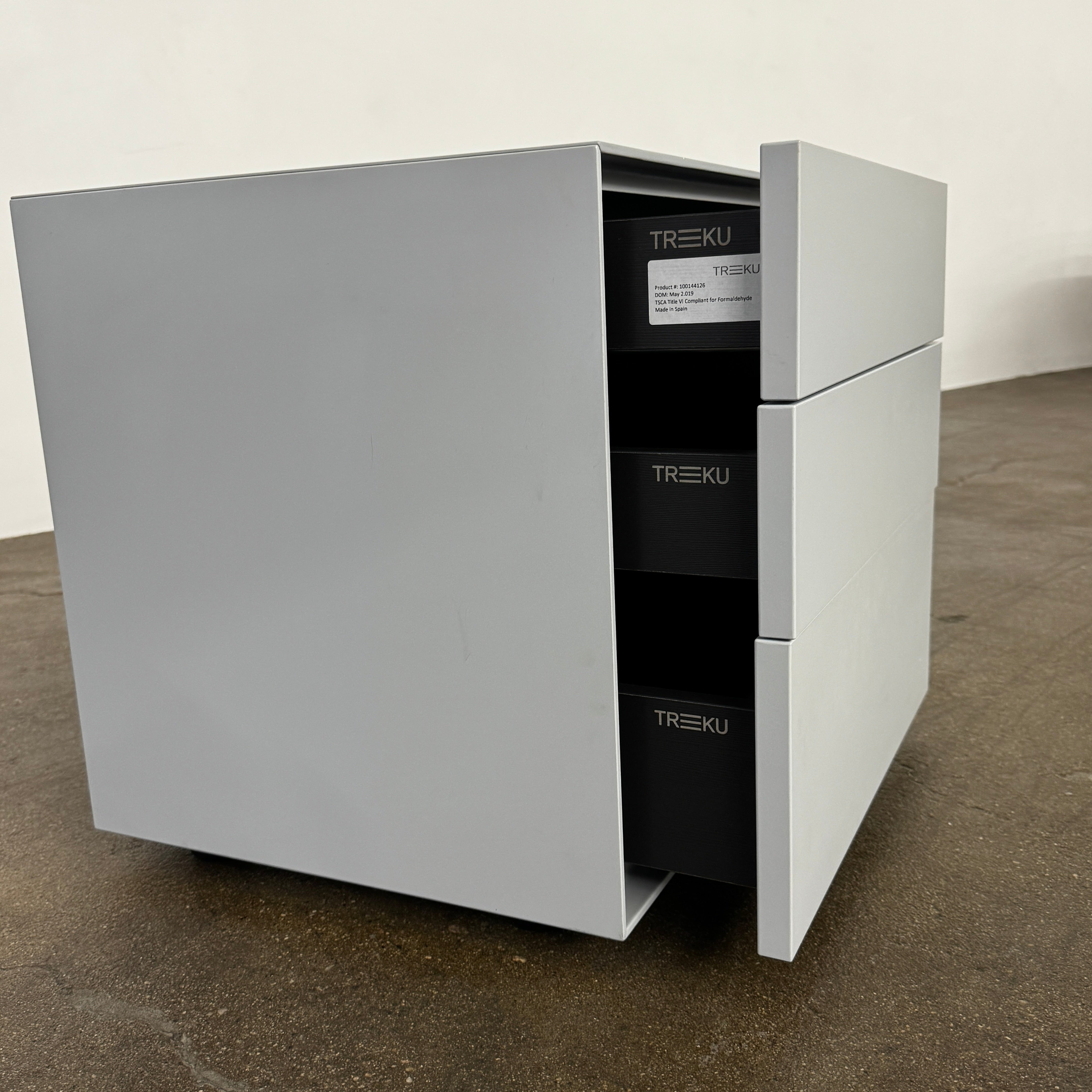 The Treku Lauki collection Side Table (2) by Treku, a gray rectangular side table with three drawers and a minimalist design, is shown against a plain white background.