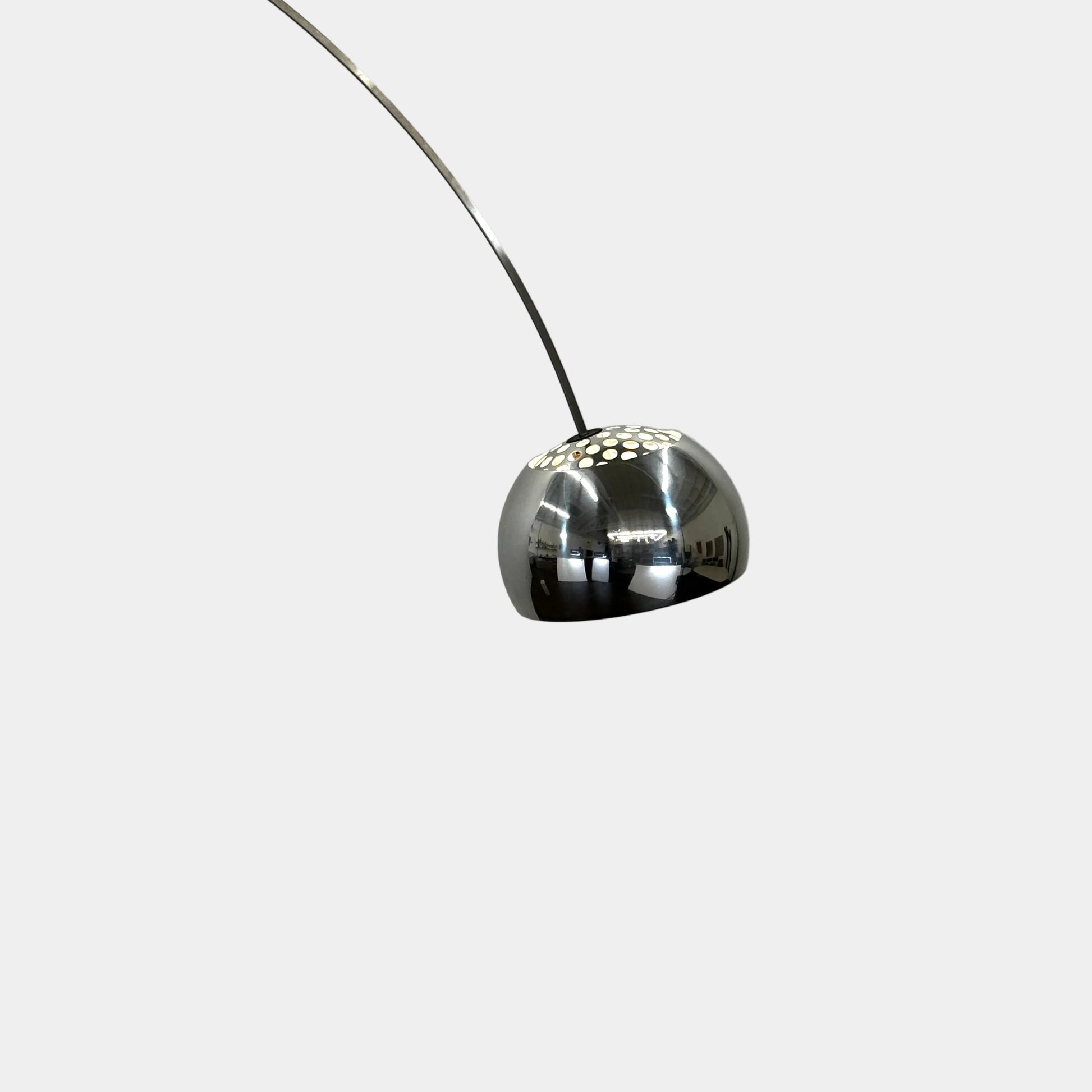 The Flos Arco Floor Lamp by Flos features a curved metal arm, dome-shaped metallic shade, and a rectangular marble base, inspired by the iconic original design.