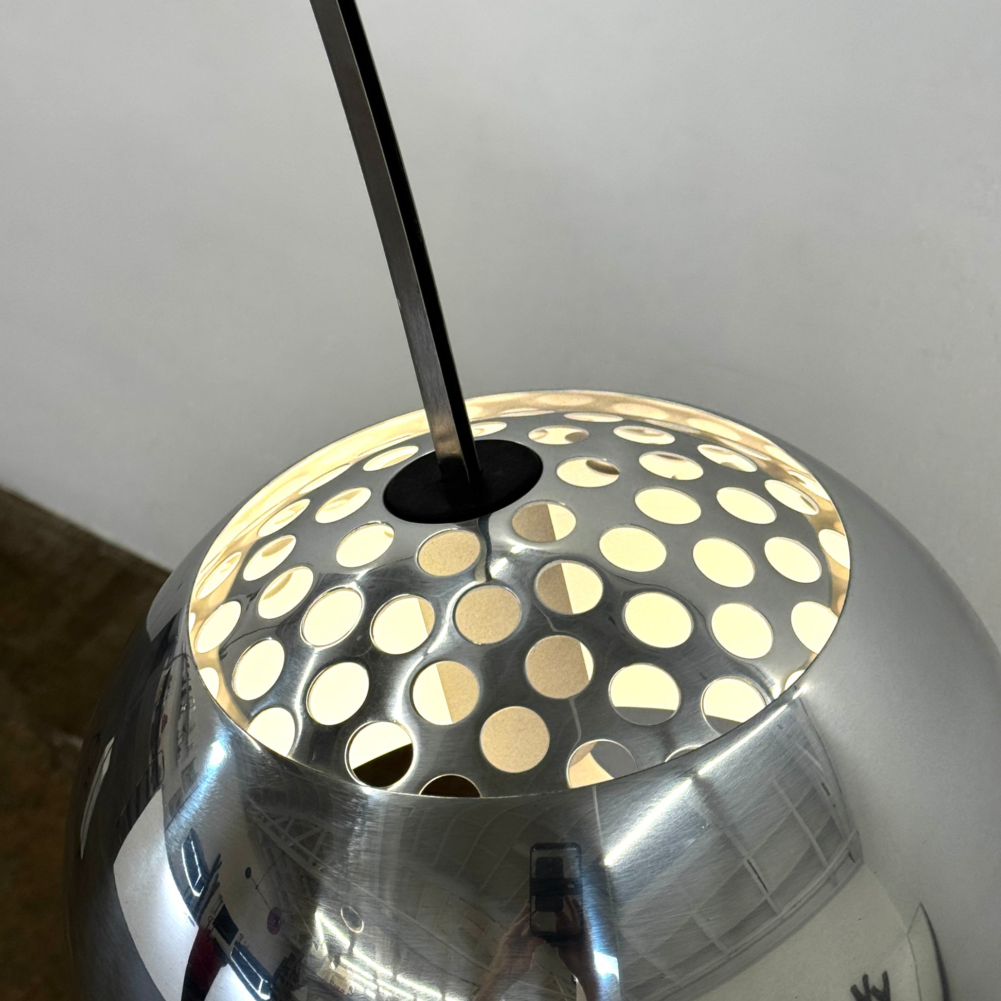 The Flos Arco Floor Lamp by Flos features a curved metal arm, dome-shaped metallic shade, and a rectangular marble base, inspired by the iconic original design.