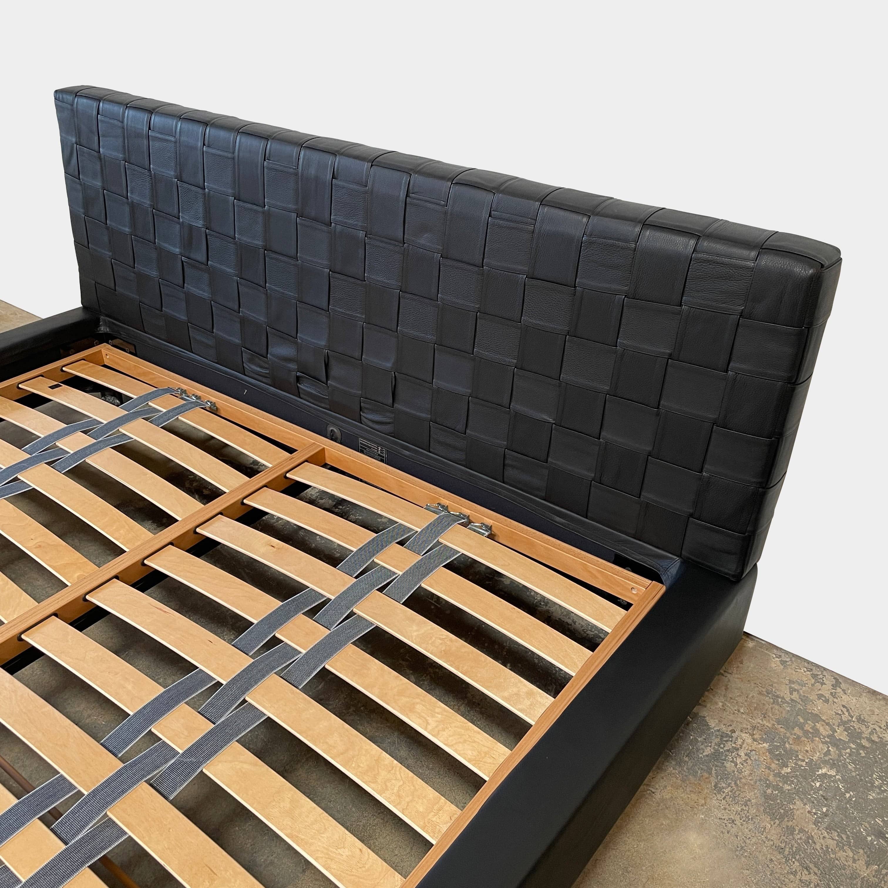 A Minotti Bartlett Cal King Bed with a wooden slatted base.