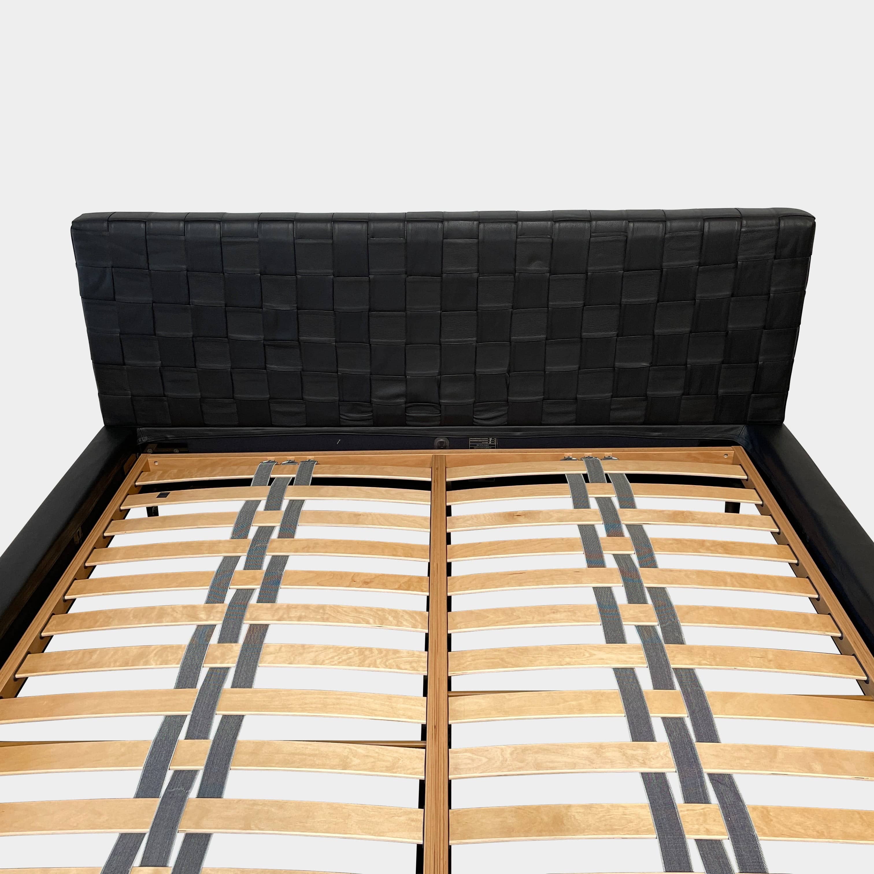 A Minotti Bartlett Cal King Bed with a wooden slatted base.