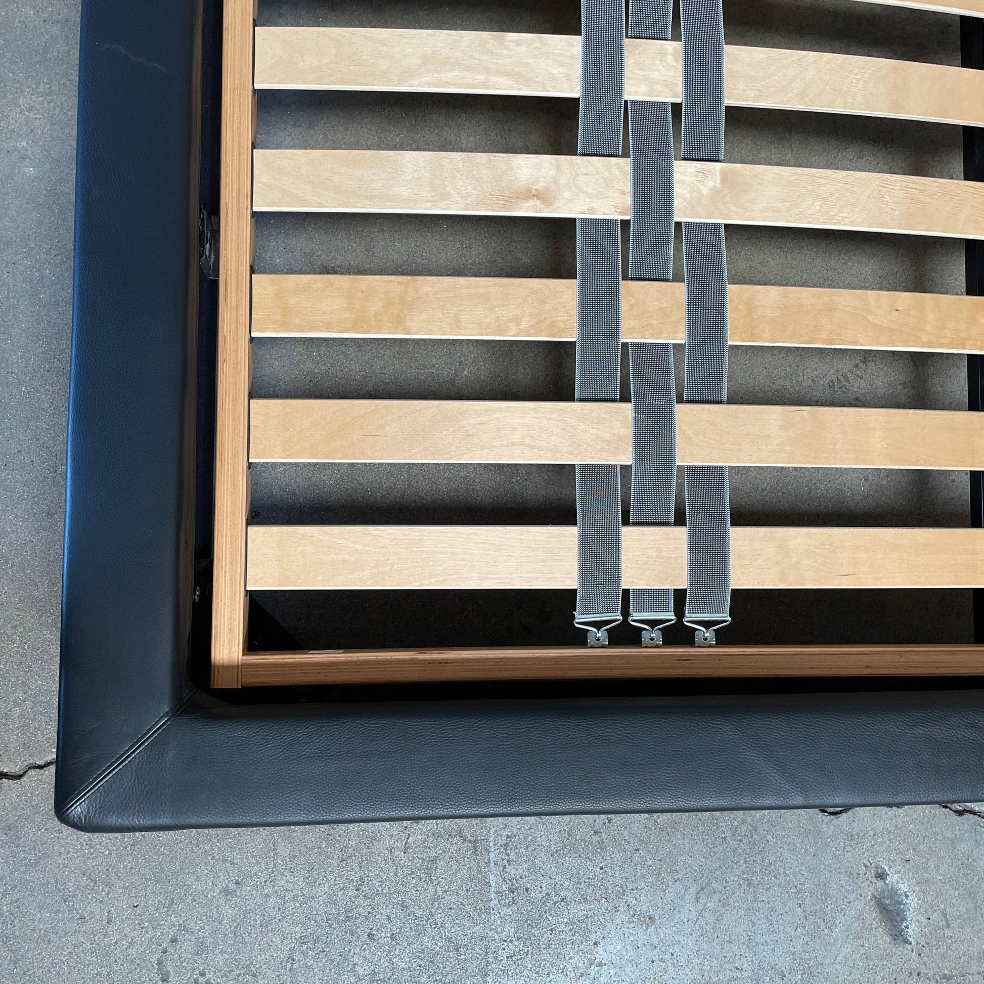 A Minotti Bartlett Cal King Bed with a wooden slatted base.