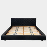 A Minotti Bartlett Cal King Bed with a wooden slatted base.