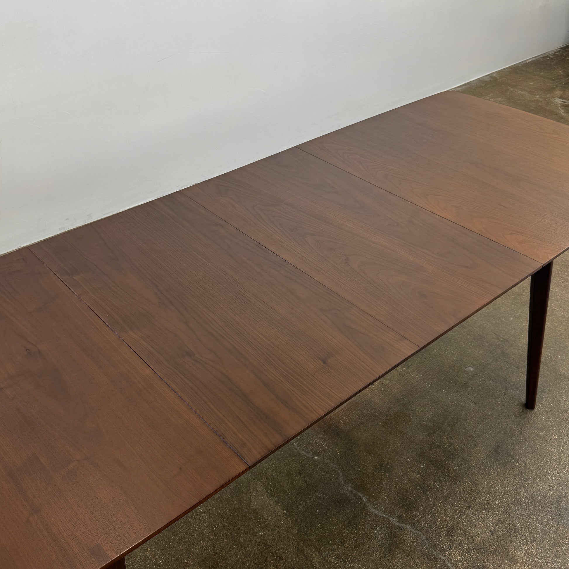 The Case Design Dulwich Extension Table by Case is an elegant rectangular walnut dining table with four legs and a smooth, flat surface, viewed from the front against a plain white background—ideal for modern dining spaces.