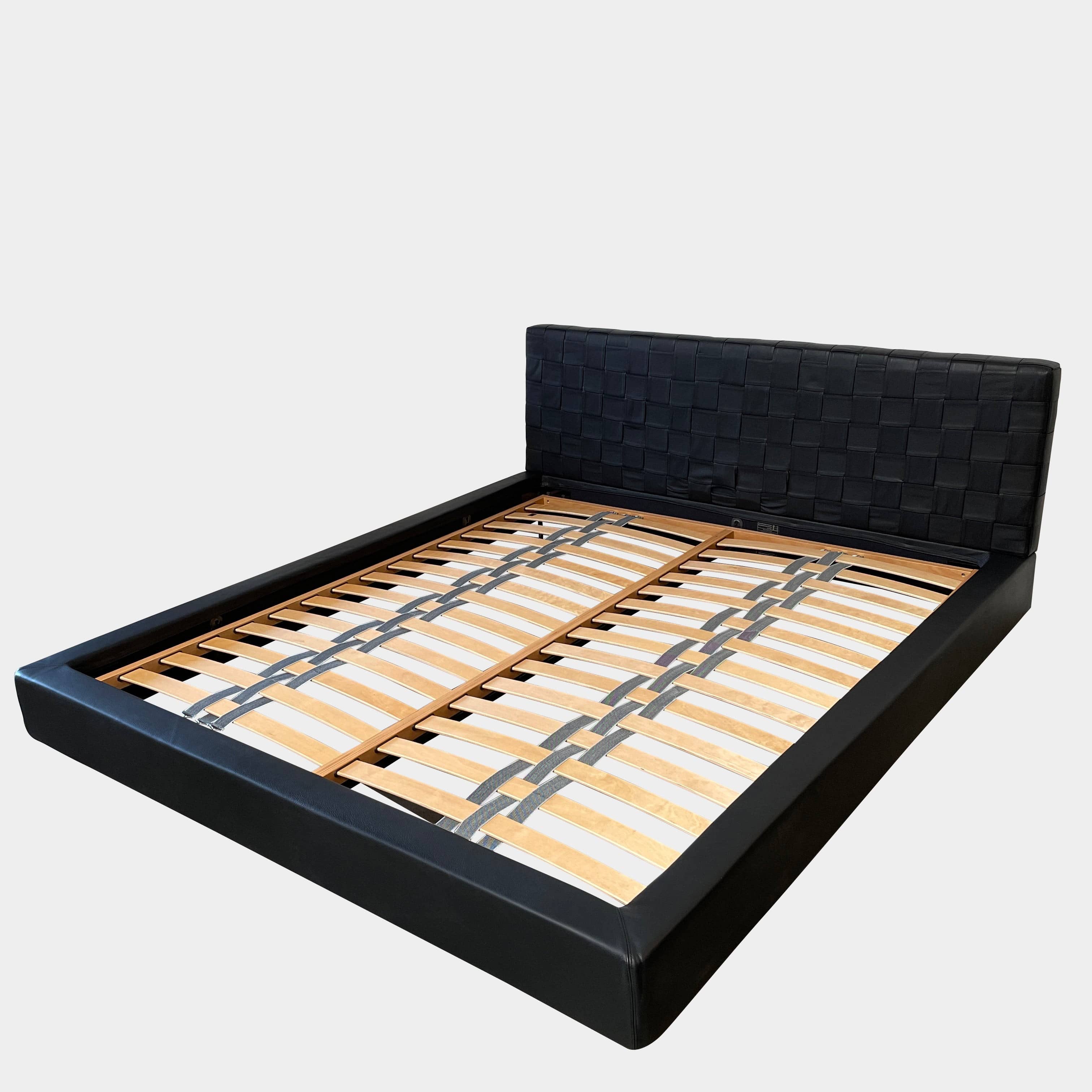 A Minotti Bartlett Cal King Bed with a wooden slatted base.