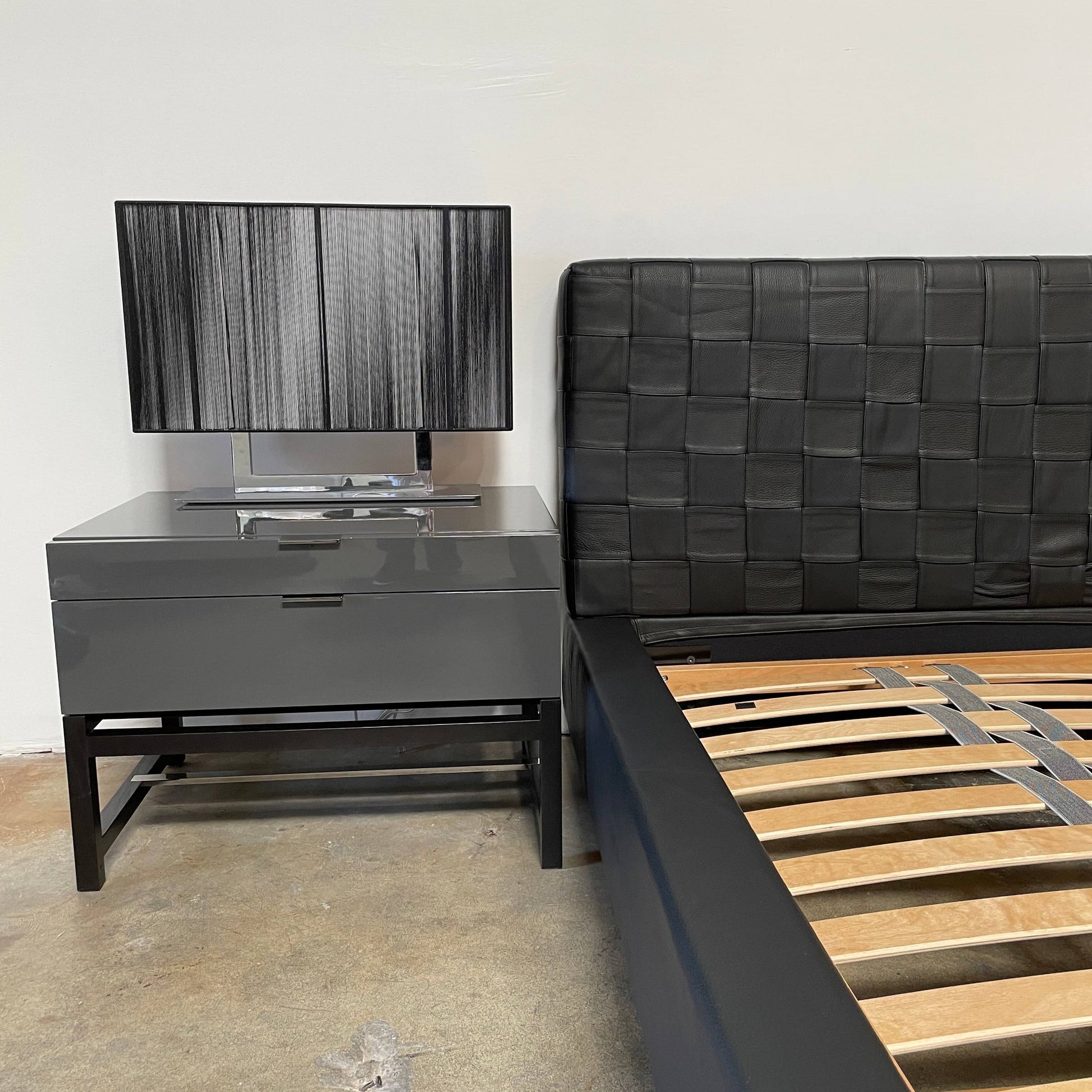 A Minotti Bartlett Cal King Bed with a wooden slatted base.