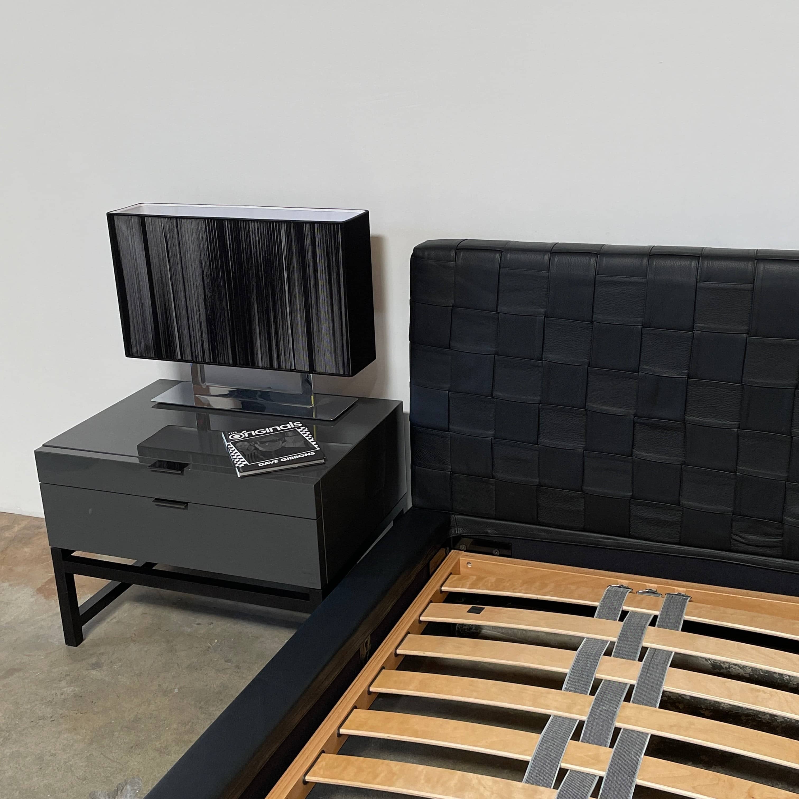 A Minotti Bartlett Cal King Bed with a wooden slatted base.