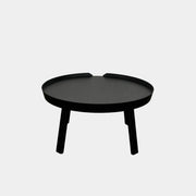 The Muuto Around Coffee Table by Muuto is a round, black wooden table with three legs and Scandinavian design, displayed against a plain light background.