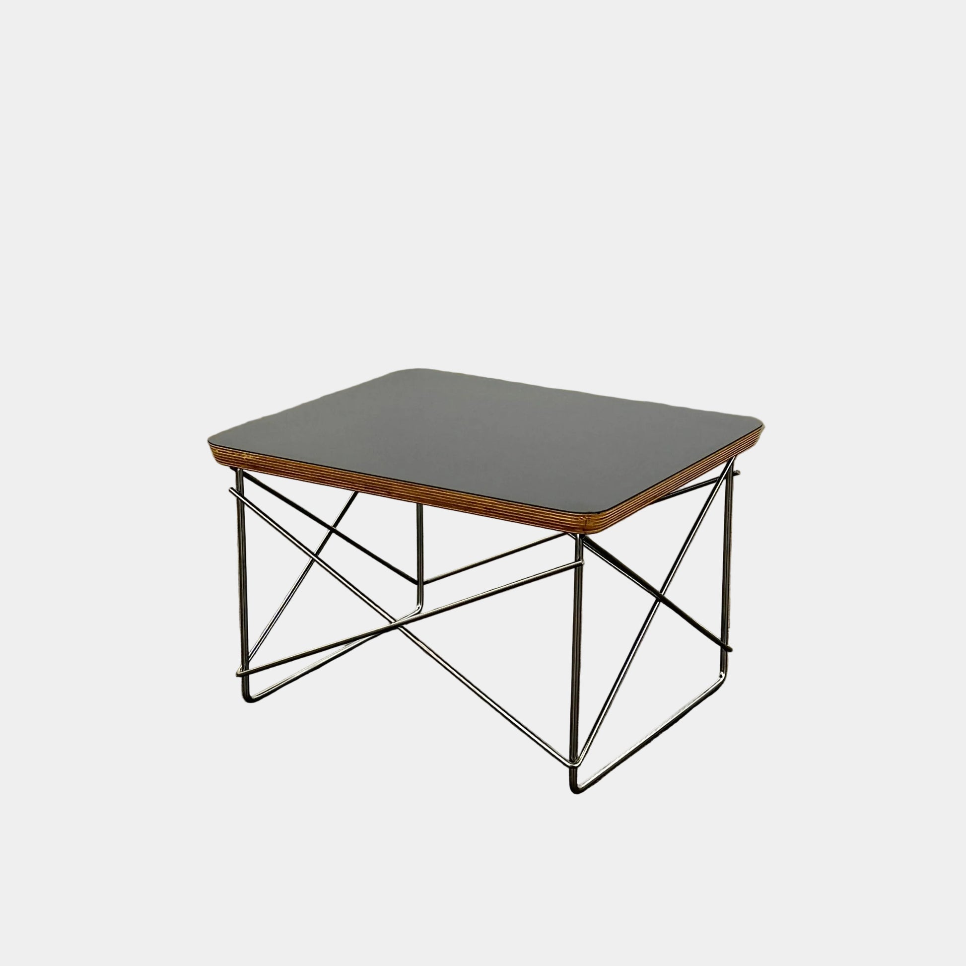 Two Herman Miller Eames Wire Base Low Tables are set side by side on a light wood floor in a bright, minimalist room, showcasing the iconic design and craftsmanship of Herman Miller.