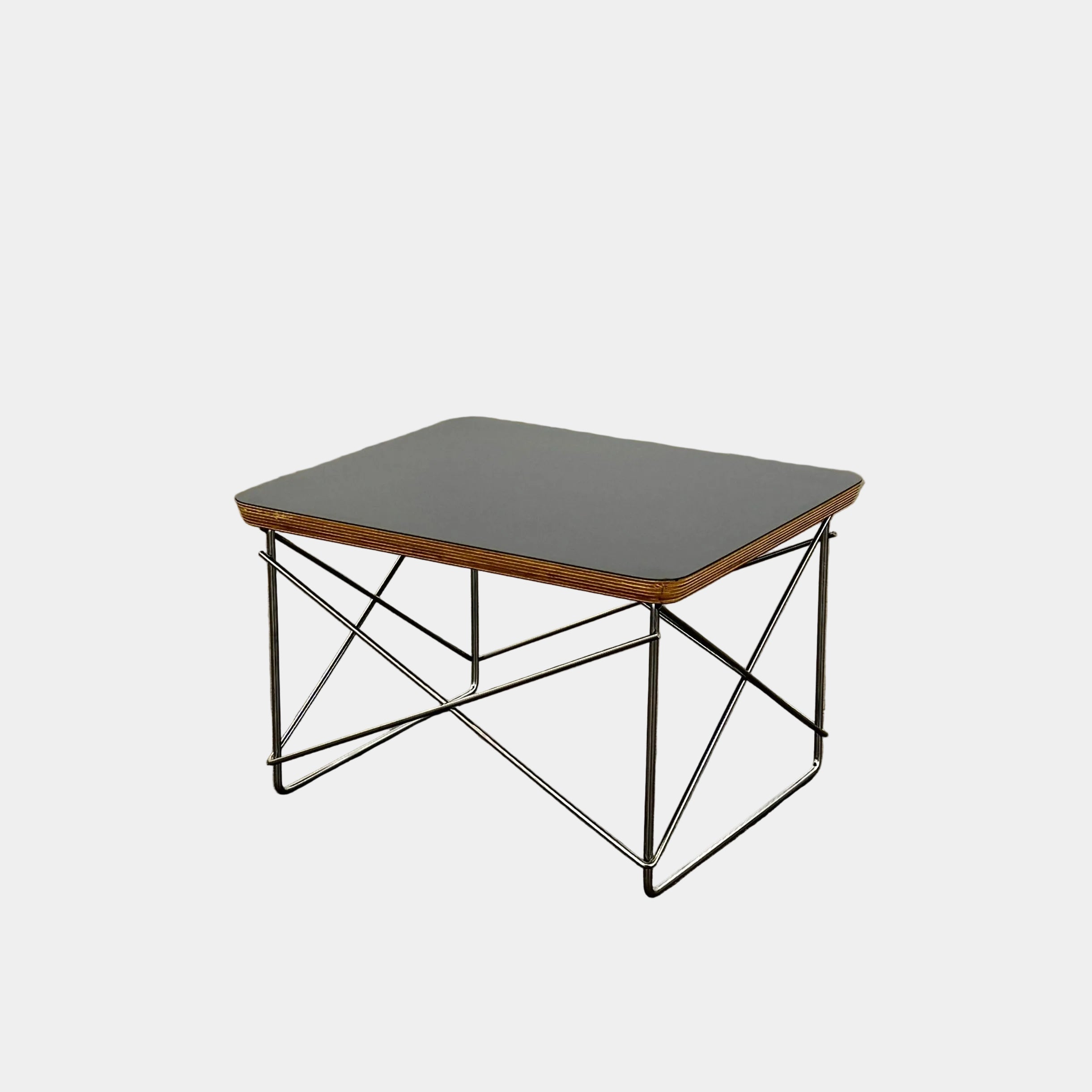 Two Herman Miller Eames Wire Base Low Tables are set side by side on a light wood floor in a bright, minimalist room, showcasing the iconic design and craftsmanship of Herman Miller.