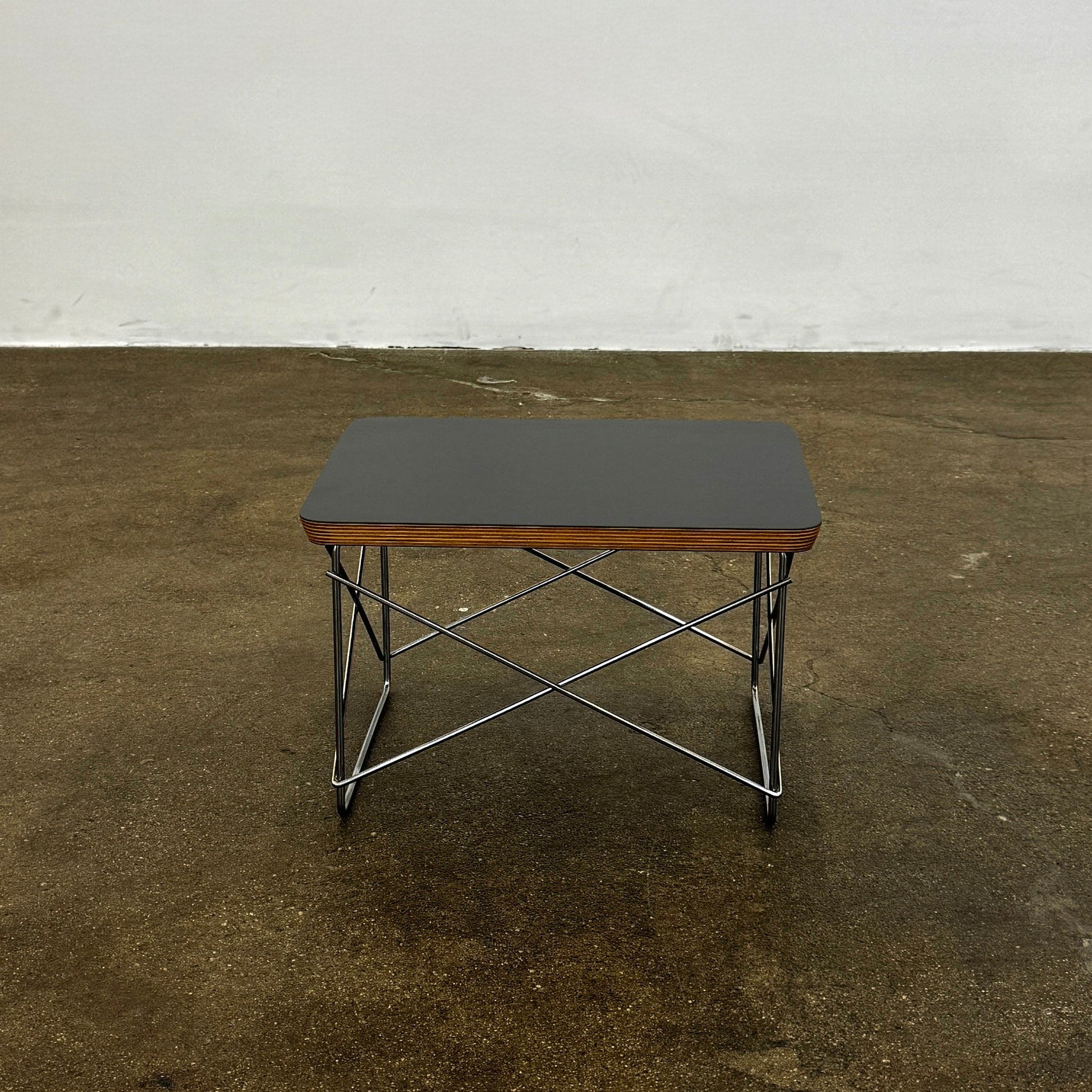 Two Herman Miller Eames Wire Base Low Tables are set side by side on a light wood floor in a bright, minimalist room, showcasing the iconic design and craftsmanship of Herman Miller.