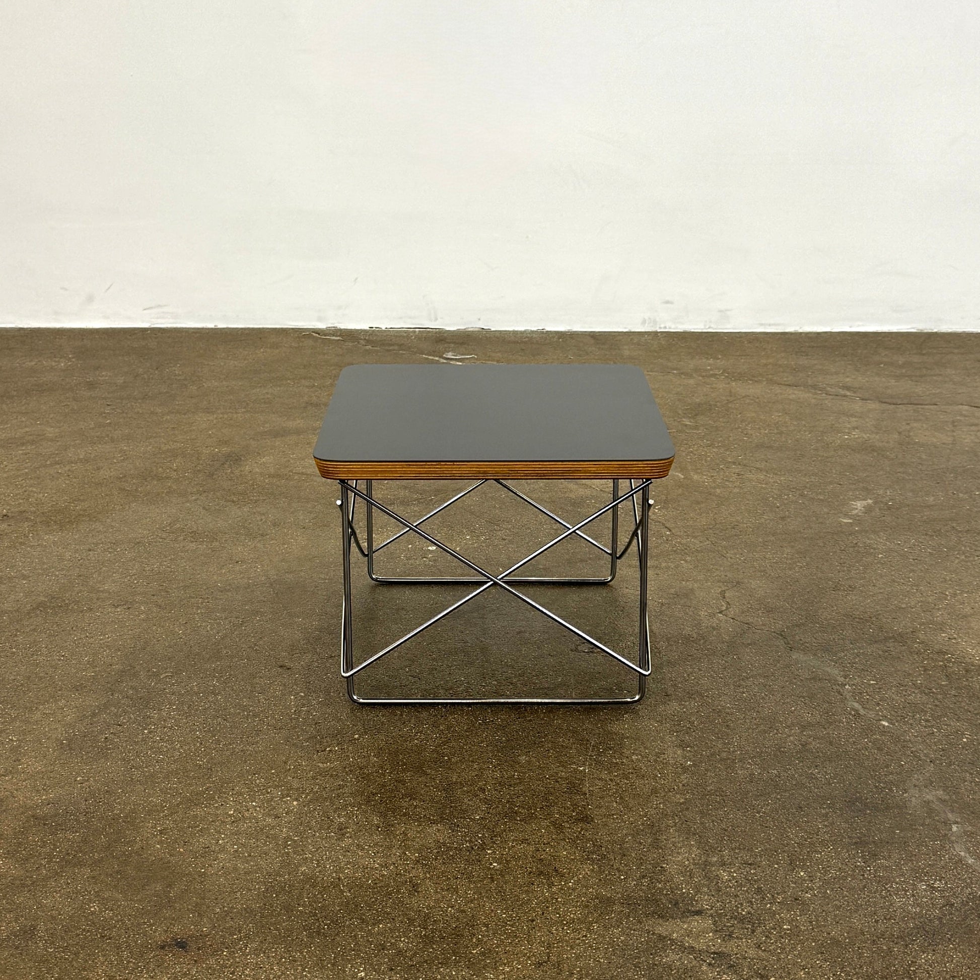 Two Herman Miller Eames Wire Base Low Tables are set side by side on a light wood floor in a bright, minimalist room, showcasing the iconic design and craftsmanship of Herman Miller.