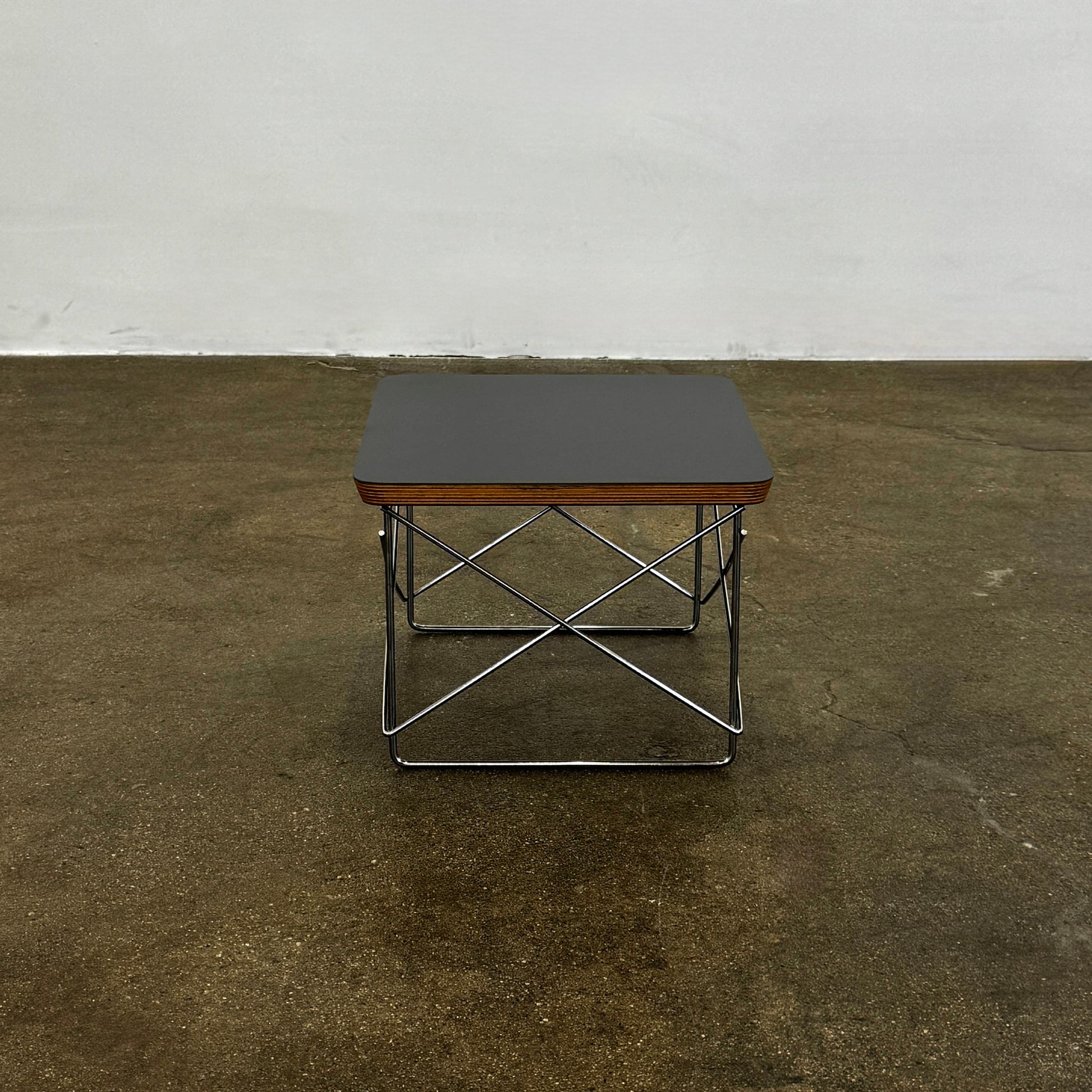 Two Herman Miller Eames Wire Base Low Tables are set side by side on a light wood floor in a bright, minimalist room, showcasing the iconic design and craftsmanship of Herman Miller.