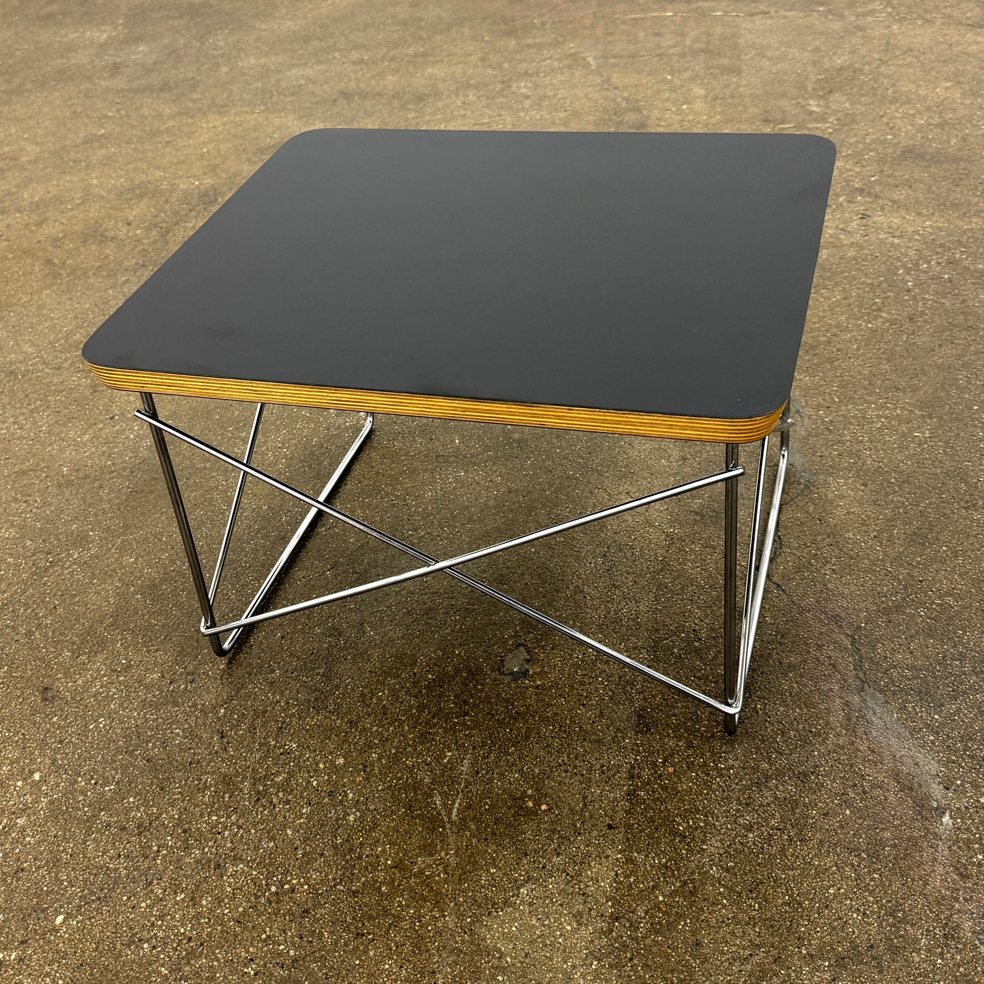 Two Herman Miller Eames Wire Base Low Tables are set side by side on a light wood floor in a bright, minimalist room, showcasing the iconic design and craftsmanship of Herman Miller.