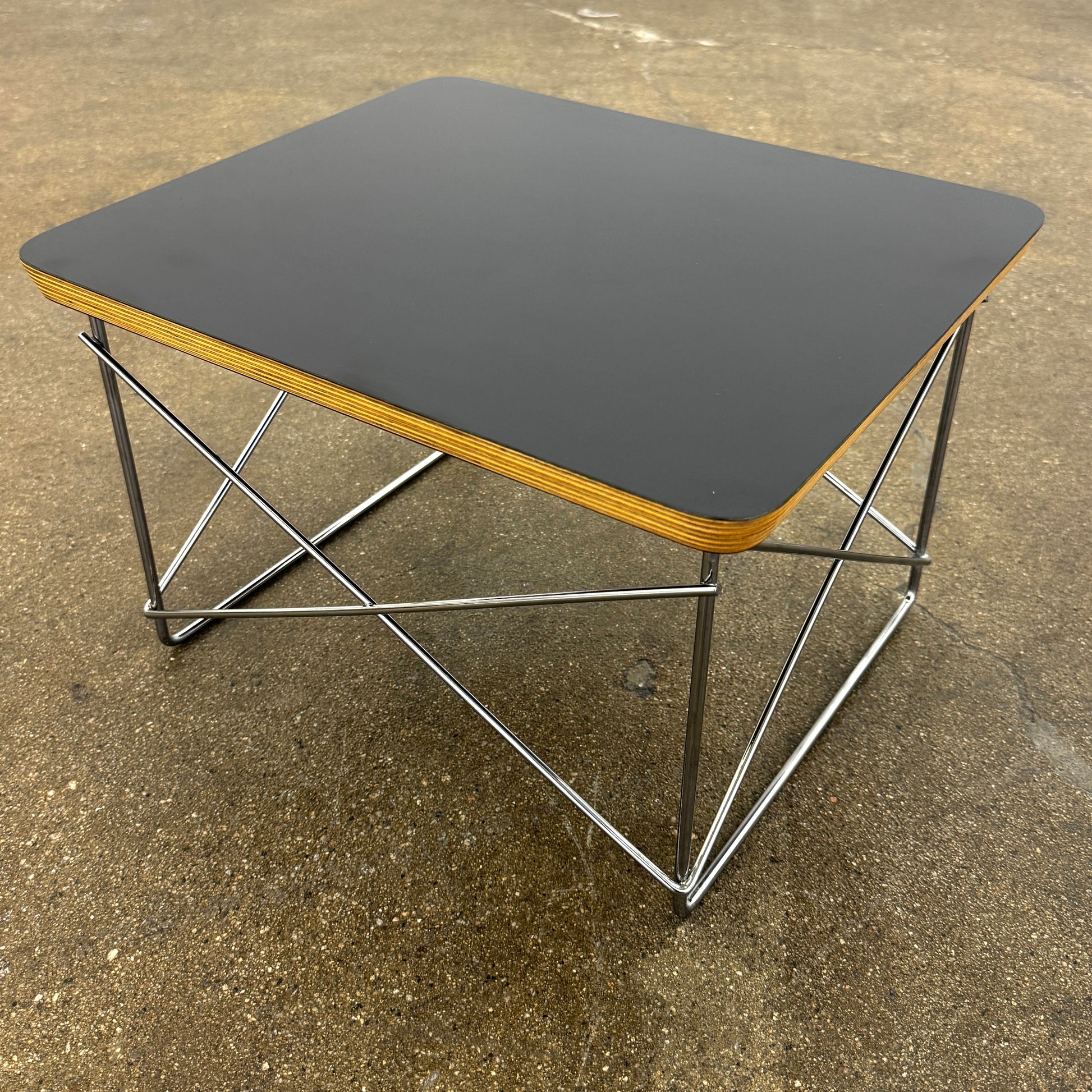 Two Herman Miller Eames Wire Base Low Tables are set side by side on a light wood floor in a bright, minimalist room, showcasing the iconic design and craftsmanship of Herman Miller.