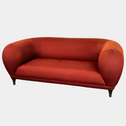 The Roche Bobois Montgolfiere Love seat is a modern, red 2-seat sofa with curved arms and dark wooden legs by Roche Bobois, shown against a plain background.