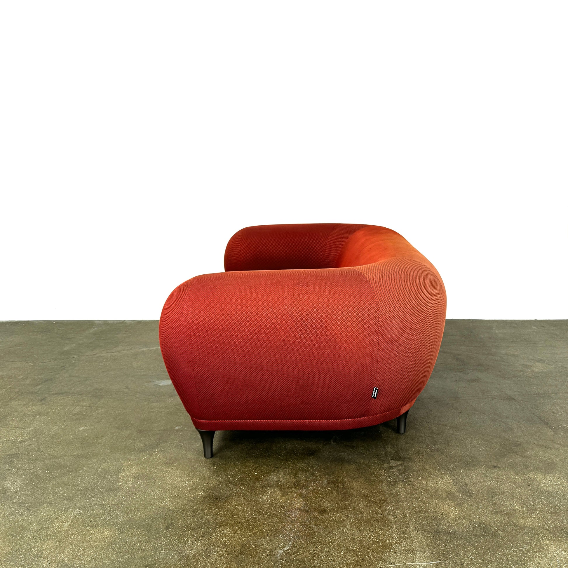 The Roche Bobois Montgolfiere Love seat is a modern, red 2-seat sofa with curved arms and dark wooden legs by Roche Bobois, shown against a plain background.