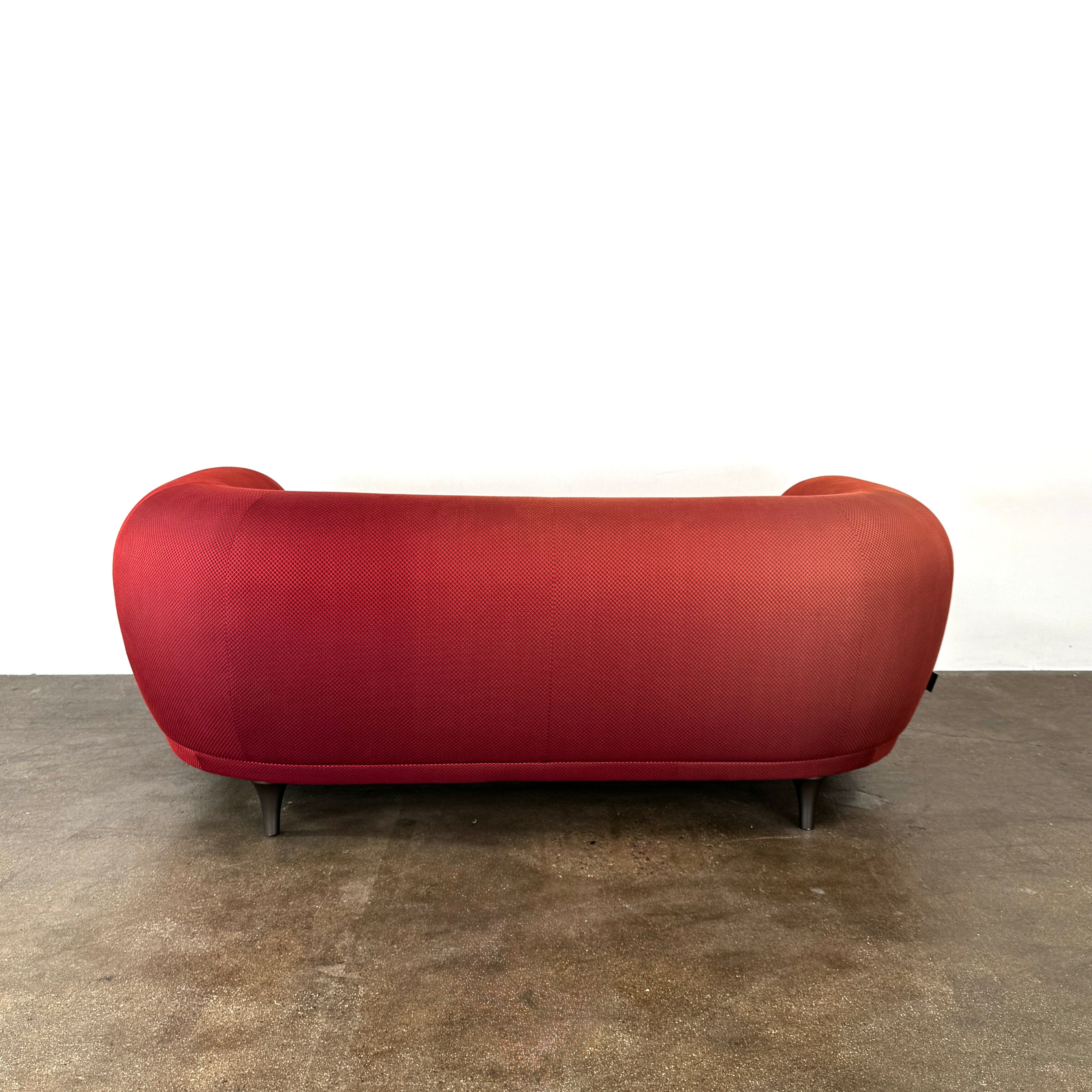 The Roche Bobois Montgolfiere Love seat is a modern, red 2-seat sofa with curved arms and dark wooden legs by Roche Bobois, shown against a plain background.