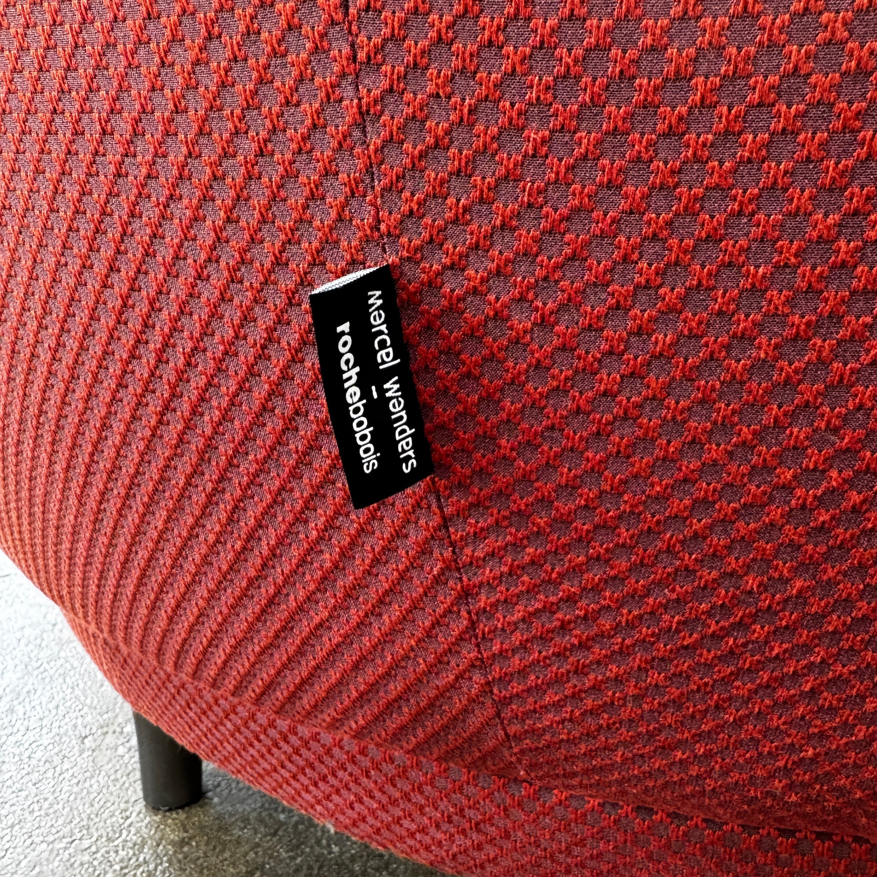 The Roche Bobois Montgolfiere Love seat is a modern, red 2-seat sofa with curved arms and dark wooden legs by Roche Bobois, shown against a plain background.