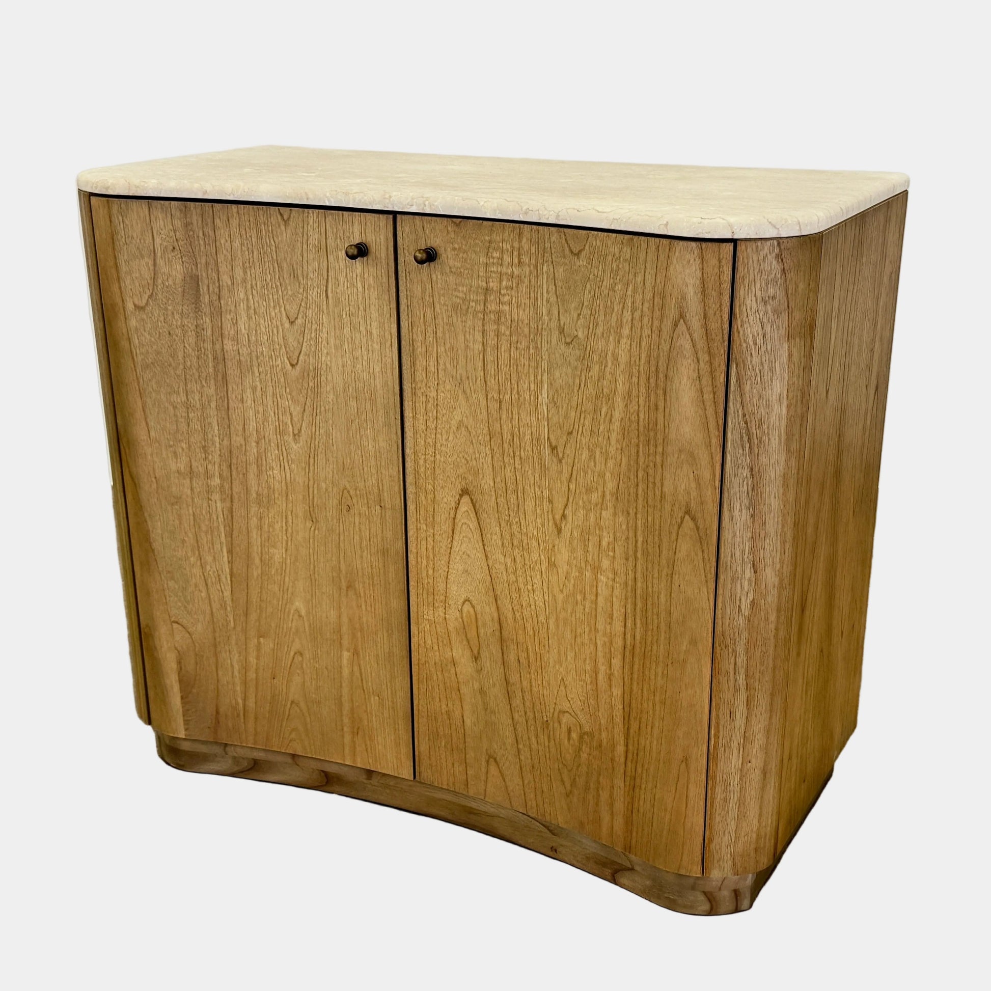 The Boa Small Cabinet by Fourhands features two doors, a gently curved front, light natural wood finish, and round handles, bringing contemporary style to any space.