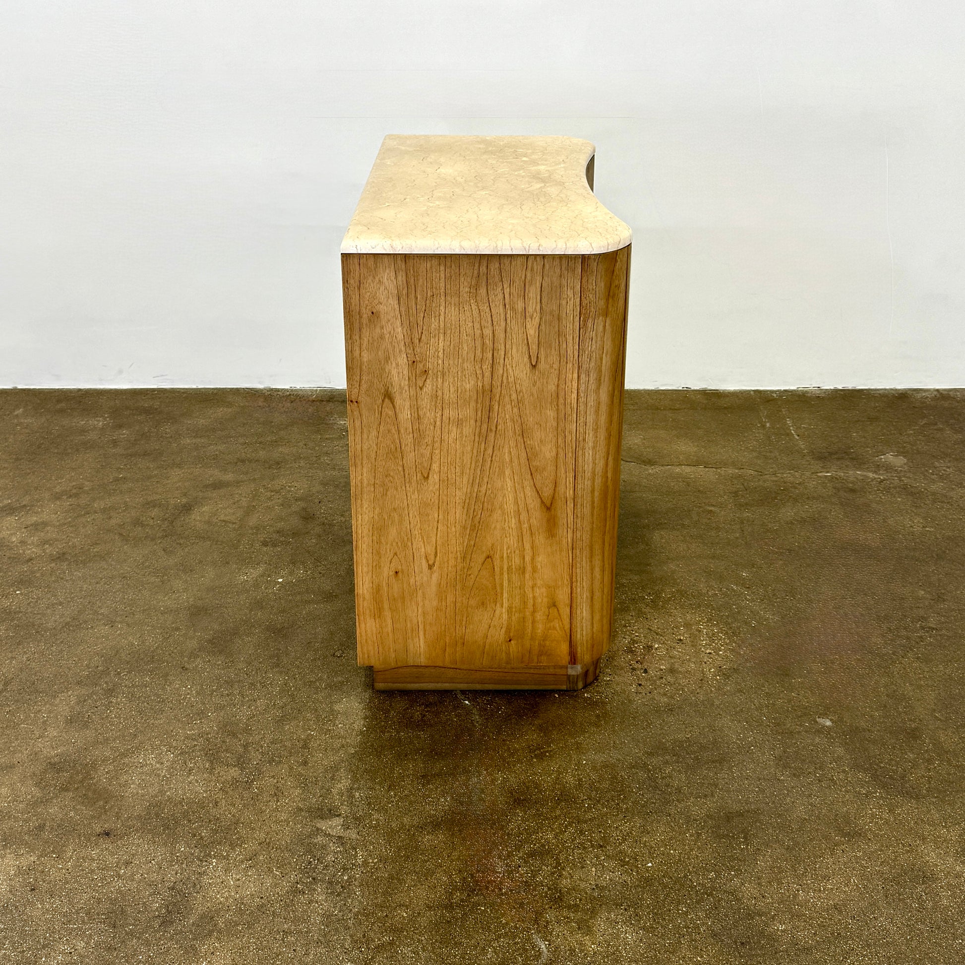The Boa Small Cabinet by Fourhands features two doors, a gently curved front, light natural wood finish, and round handles, bringing contemporary style to any space.