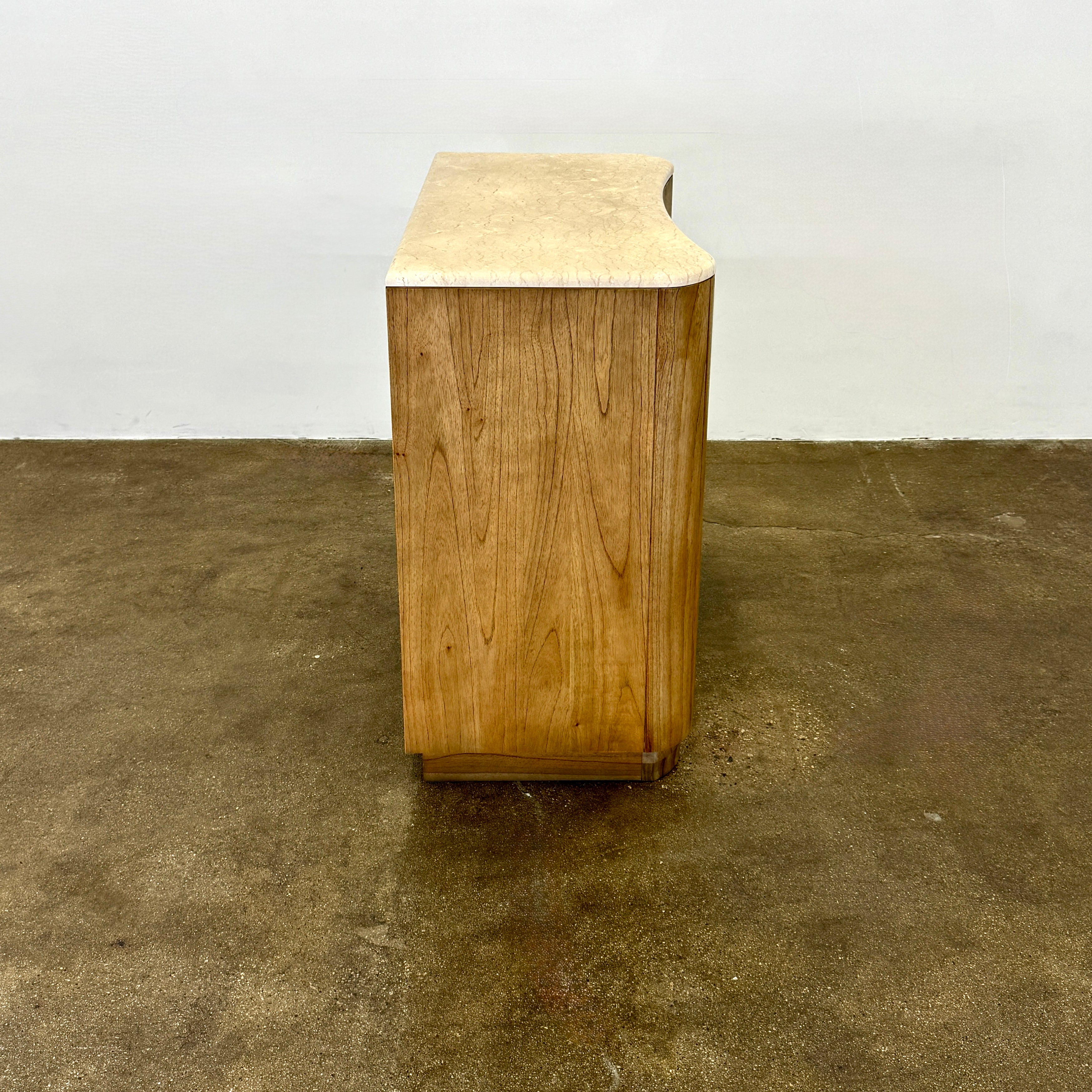 The Boa Small Cabinet by Fourhands features two doors, a gently curved front, light natural wood finish, and round handles, bringing contemporary style to any space.