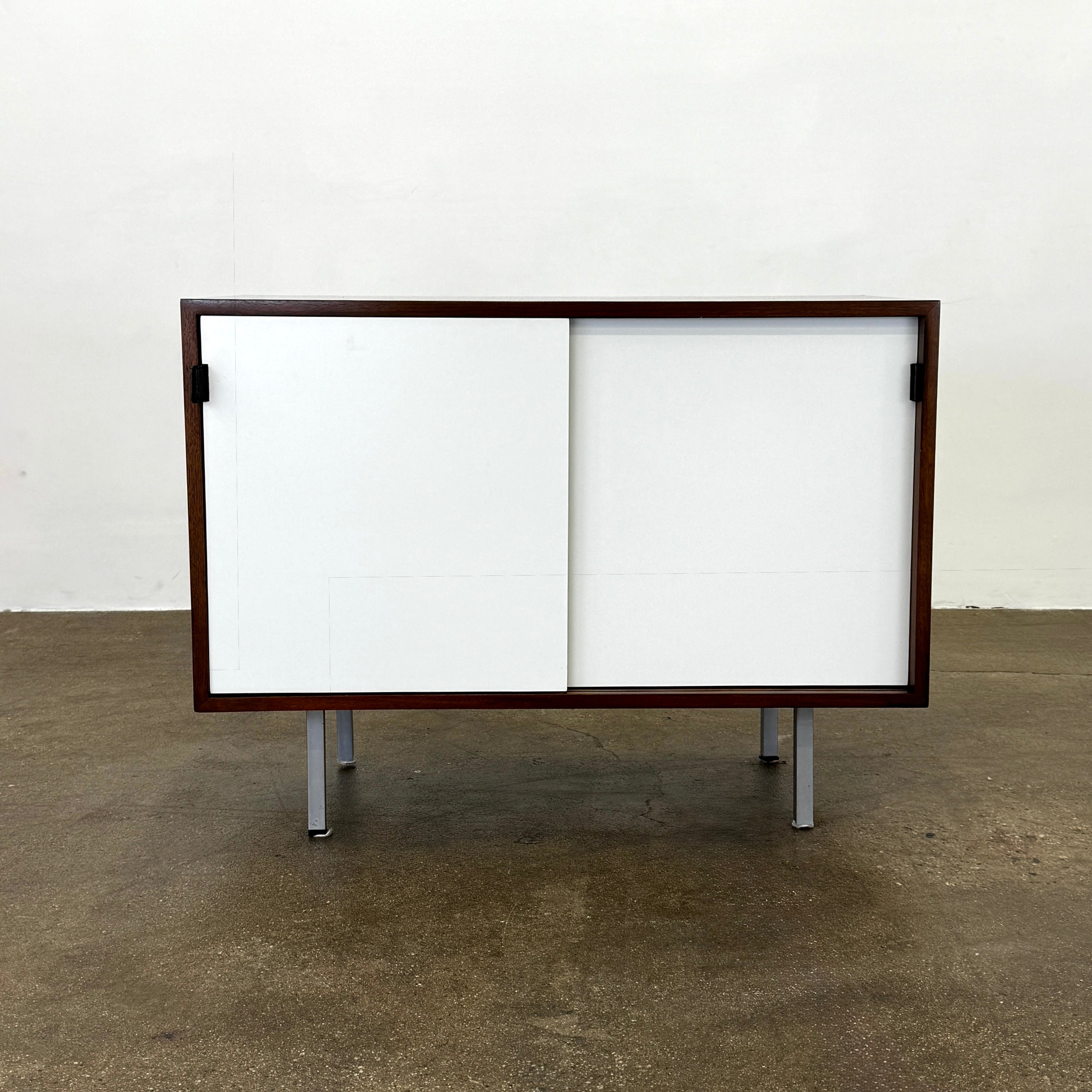 The Knoll Vintage Florence Knoll Office Storage features a dark wood frame, white sliding doors, and metal legs—perfect as a stylish credenza or office storage against a plain white wall.