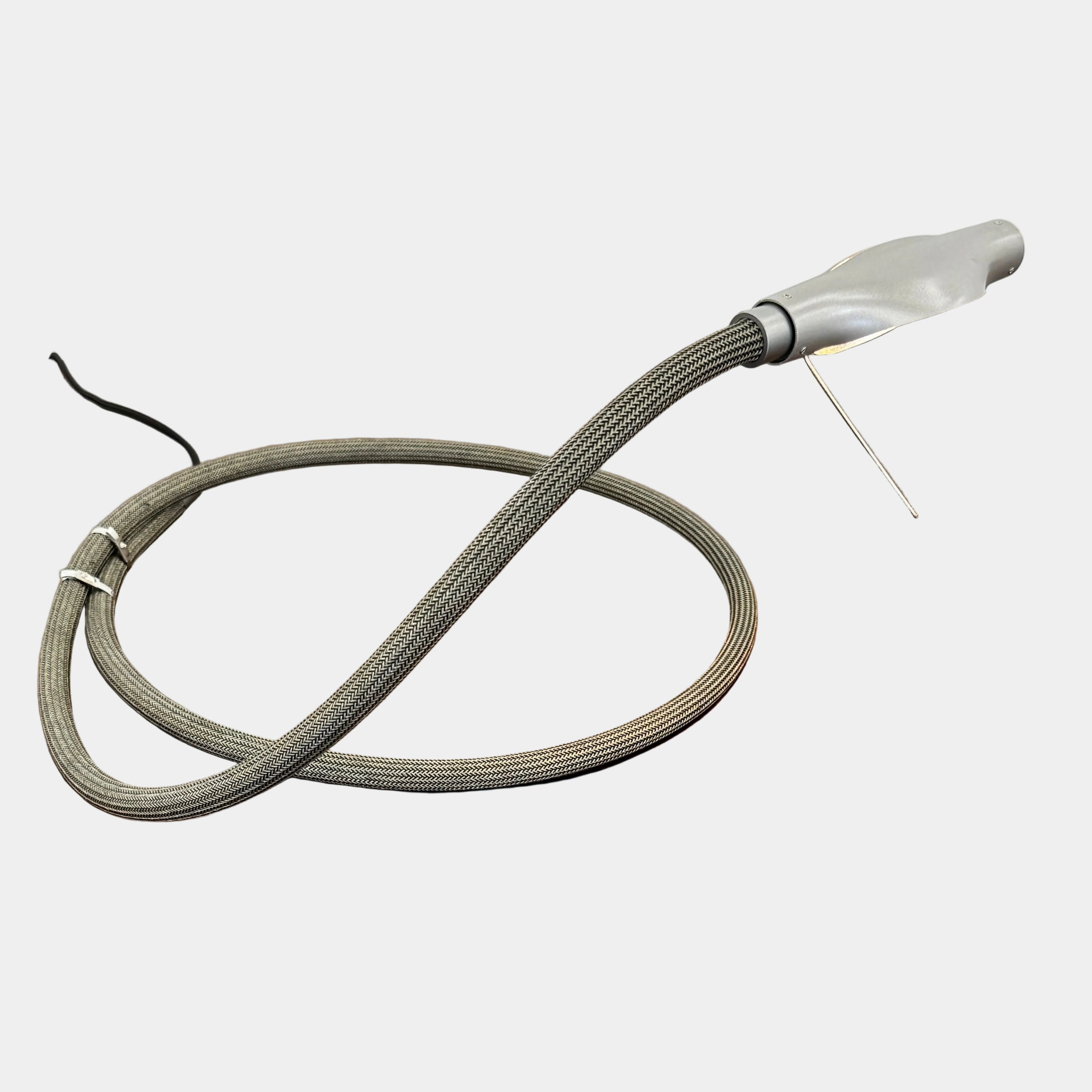 The Ingo Maurer Metall T. Cooper Task Light features a flexible metal braided hose with a metallic nozzle on one end and exposed wires on the other, coiled on a plain white background—evoking collectible German designer lighting.