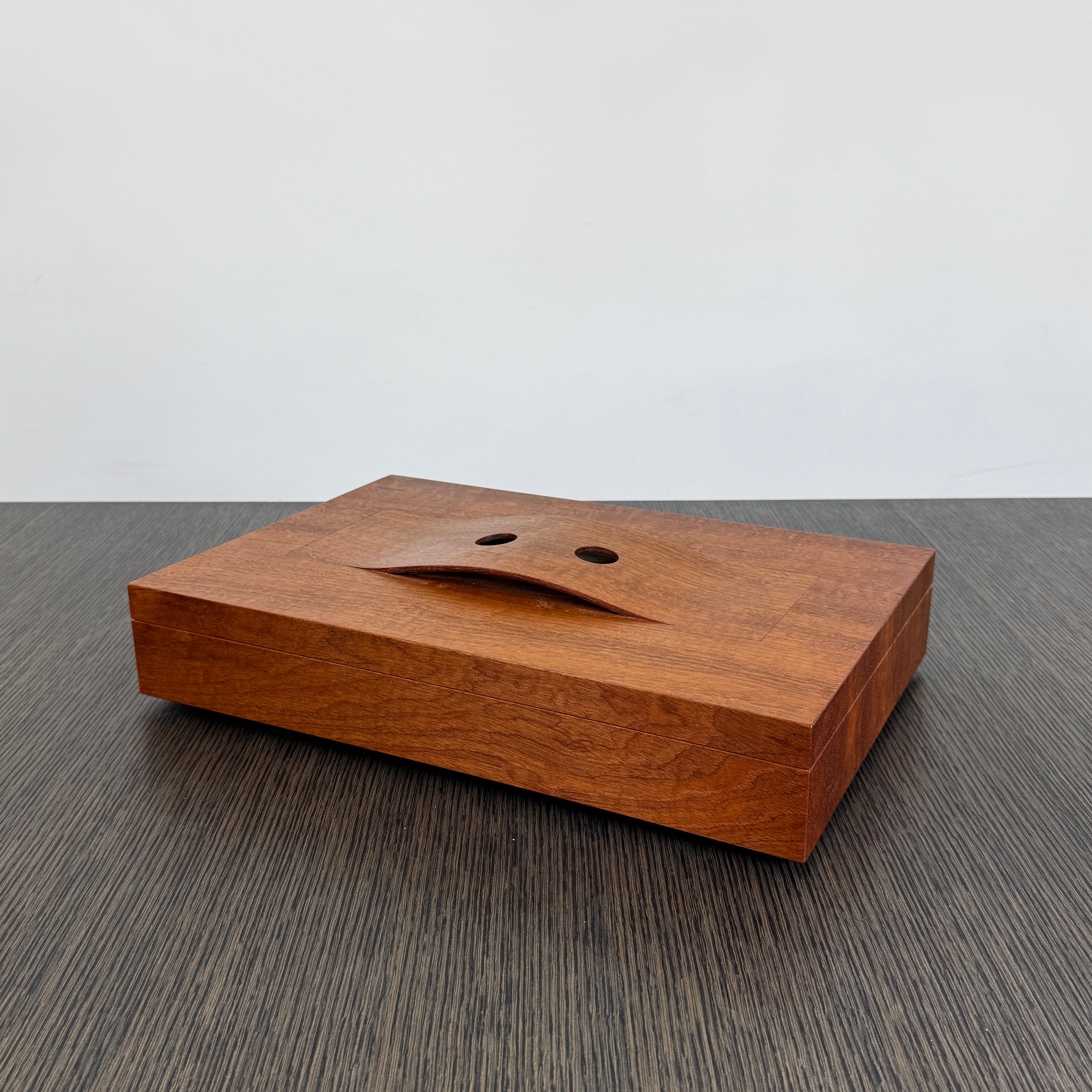 The Mike Fair Jewelry / Cigar Box by Mike Fair Custom Furnishings is a rectangular handcrafted box with a lid featuring a curved cutout and two circular holes, displayed against a plain white background.