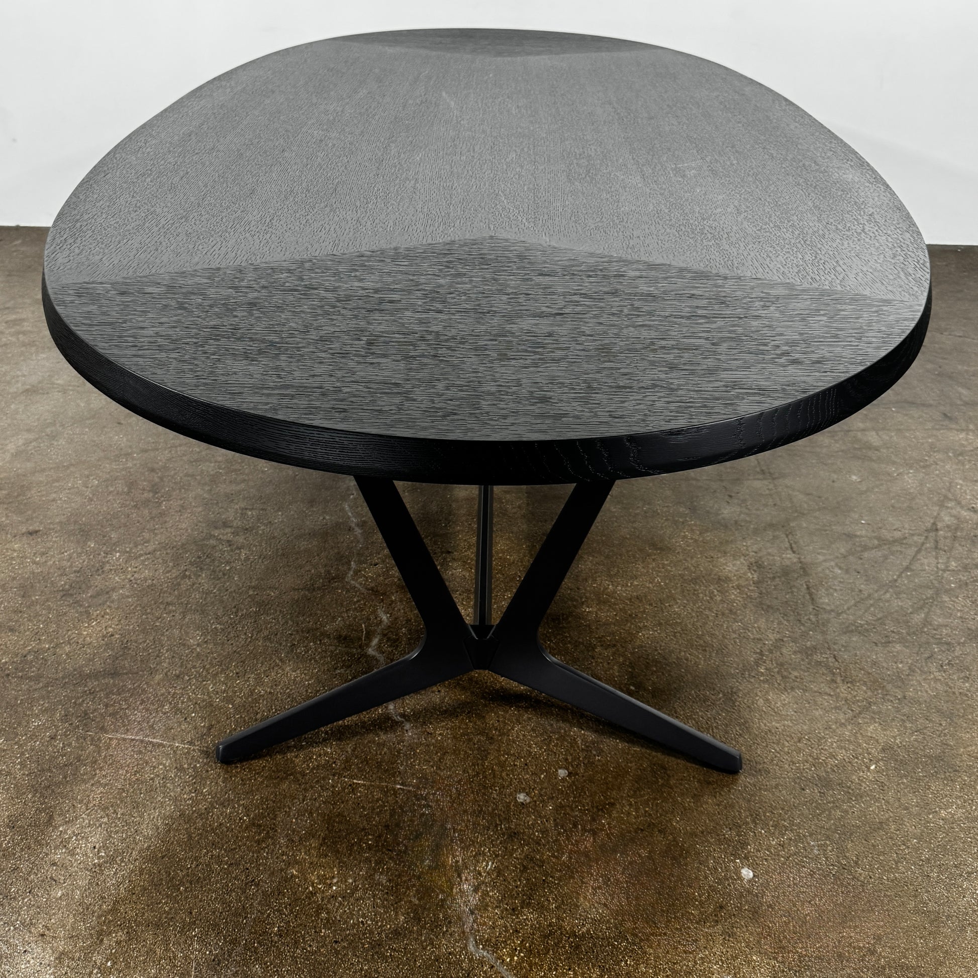 A spacious Maxalto Astrum Dining Table by Maxalto with black oak finish and bronze nickel base is paired with eight evenly arranged dark brown chairs in a minimalist setting.
