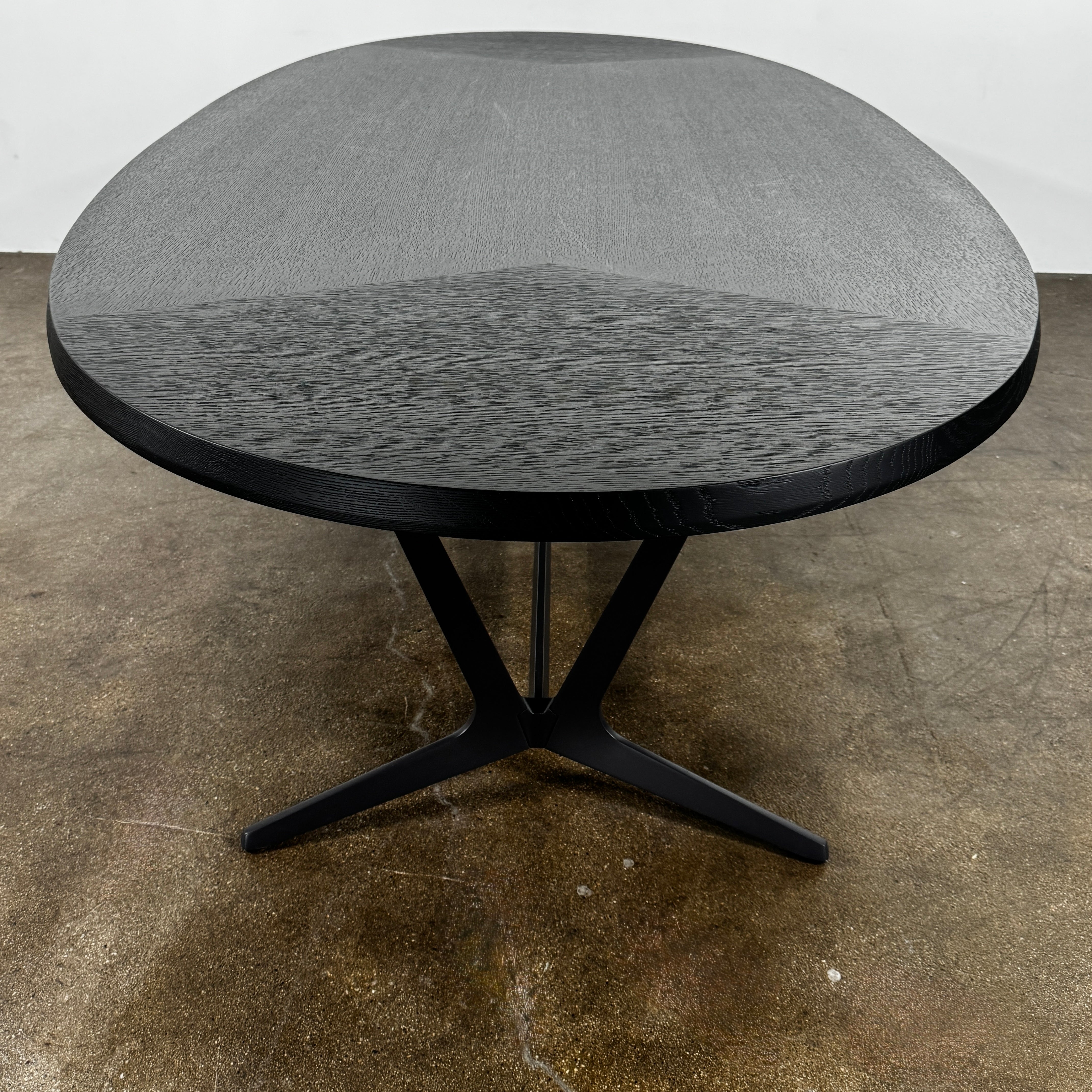 A spacious Maxalto Astrum Dining Table by Maxalto with black oak finish and bronze nickel base is paired with eight evenly arranged dark brown chairs in a minimalist setting.