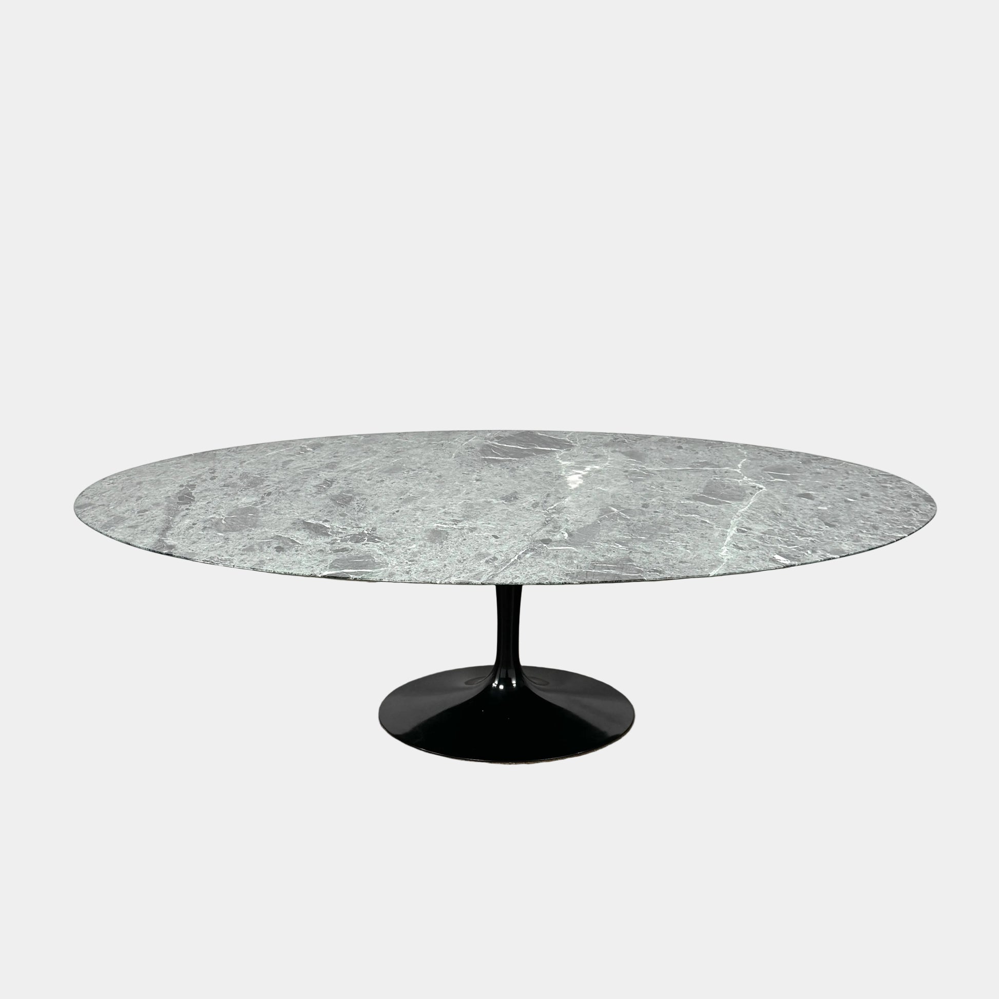 The Knoll Oval Verde Alpi Marble Saarinen Table features a gray marble top and a black pedestal base, inspired by the classic design, set against a plain white background.