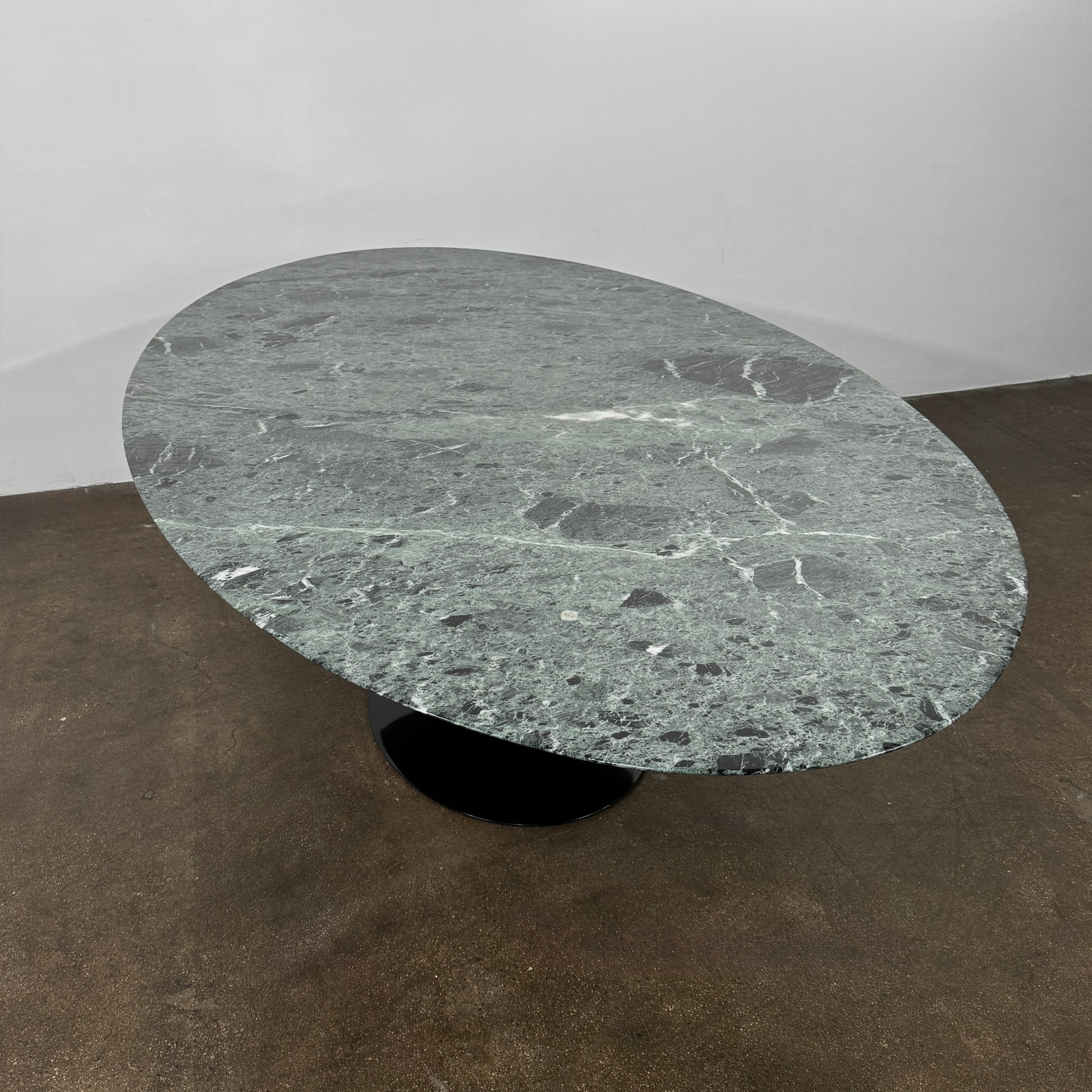 The Knoll Oval Verde Alpi Marble Saarinen Table features a gray marble top and a black pedestal base, inspired by the classic design, set against a plain white background.
