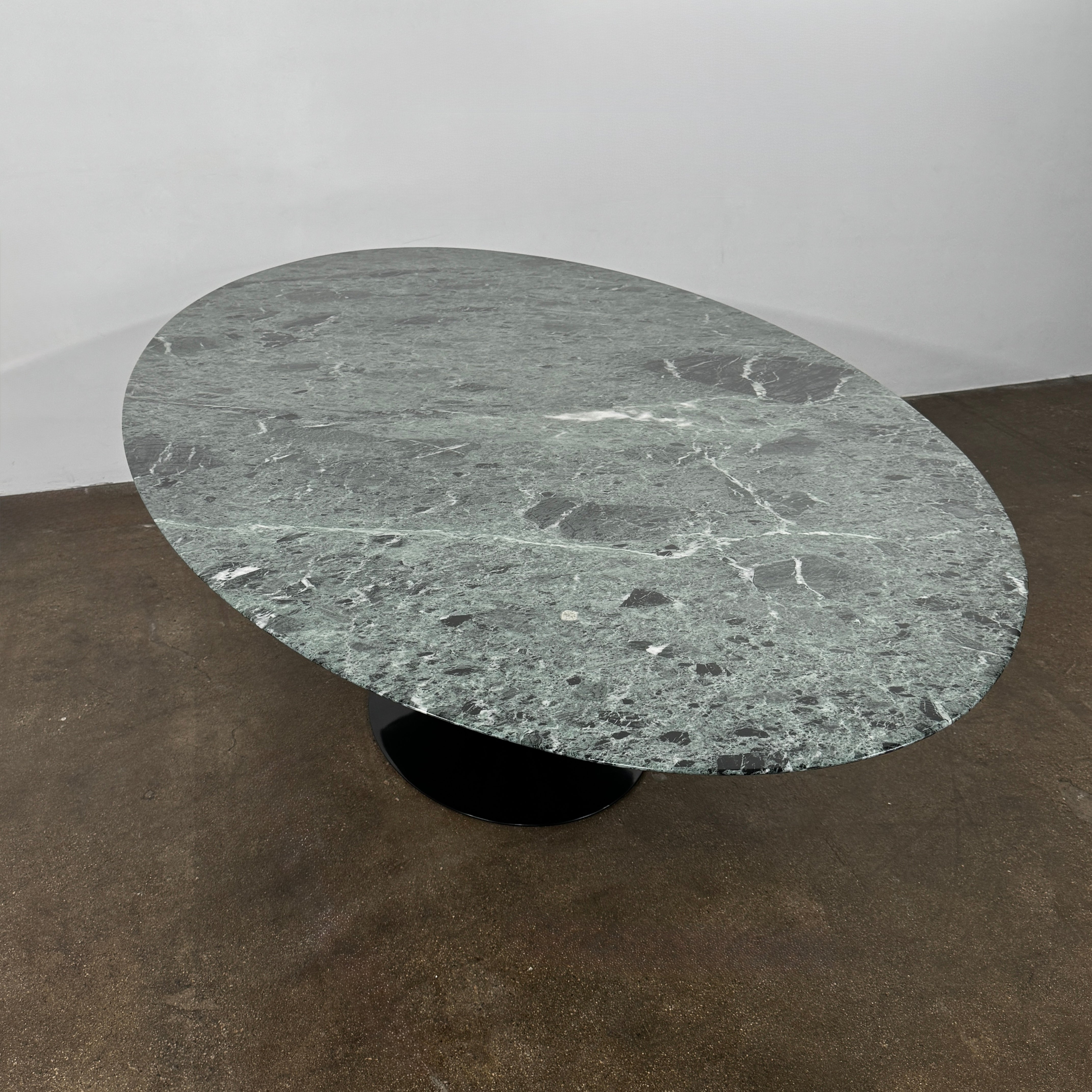 The Knoll Oval Verde Alpi Marble Saarinen Table features a gray marble top and a black pedestal base, inspired by the classic design, set against a plain white background.