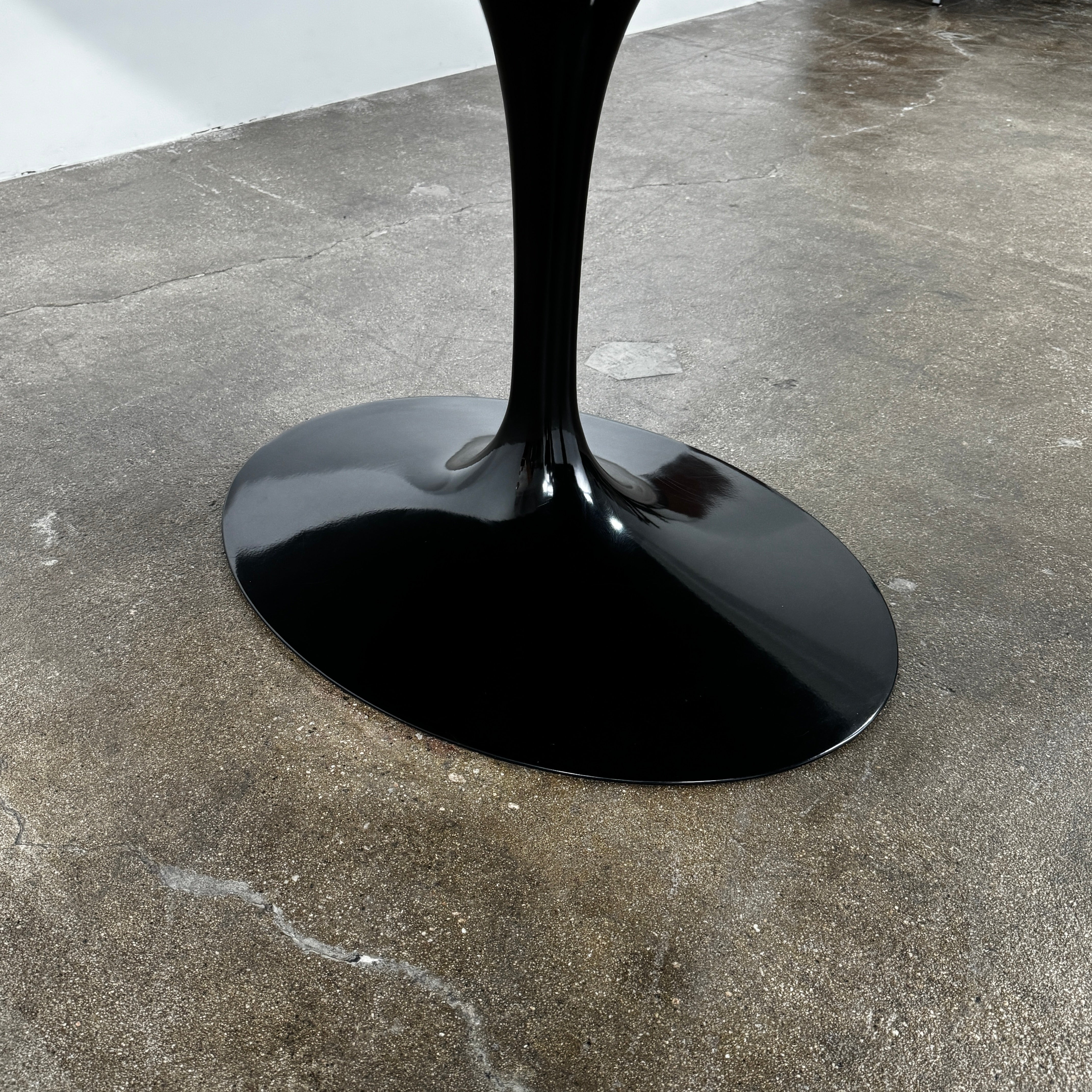 The Knoll Oval Verde Alpi Marble Saarinen Table features a gray marble top and a black pedestal base, inspired by the classic design, set against a plain white background.