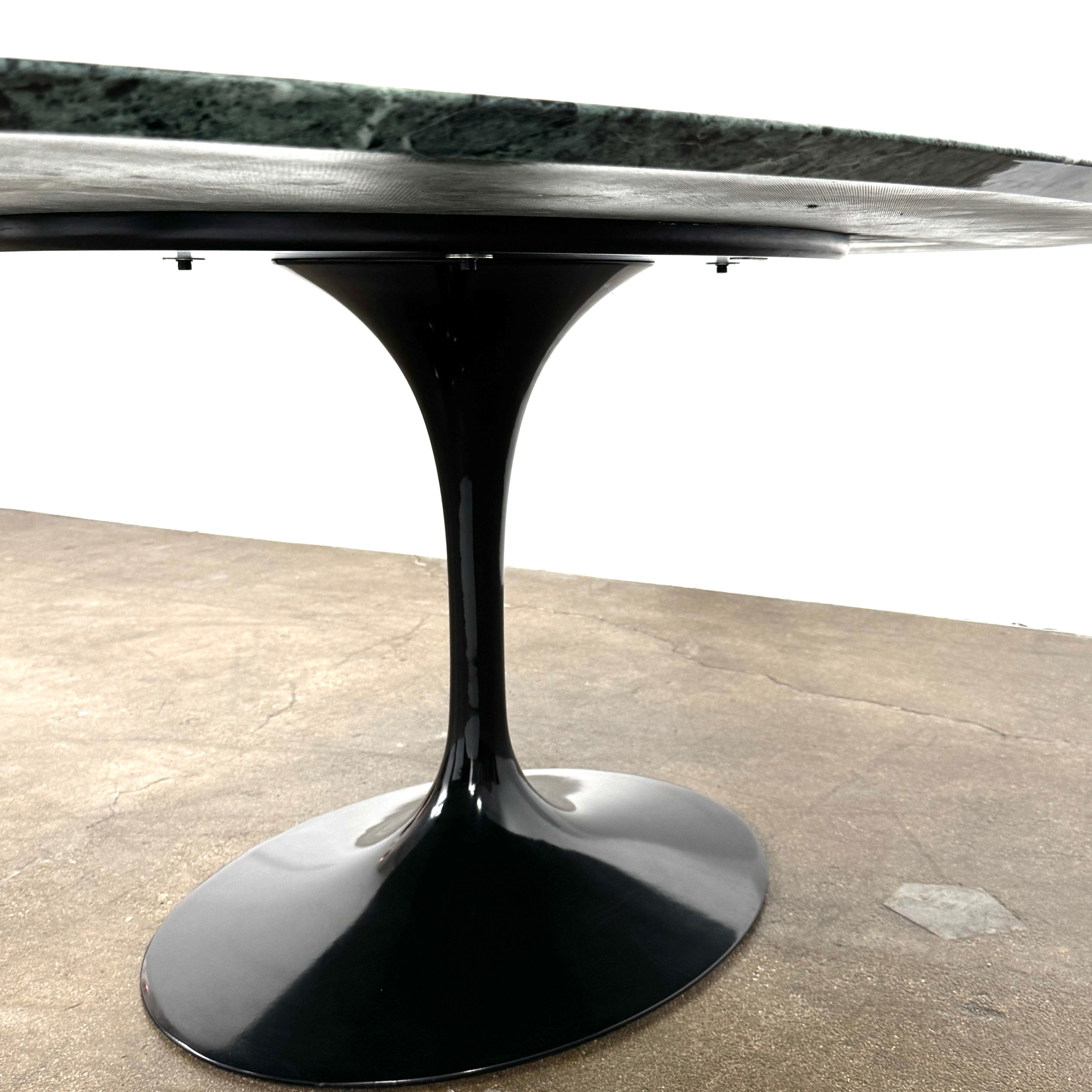 The Knoll Oval Verde Alpi Marble Saarinen Table features a gray marble top and a black pedestal base, inspired by the classic design, set against a plain white background.