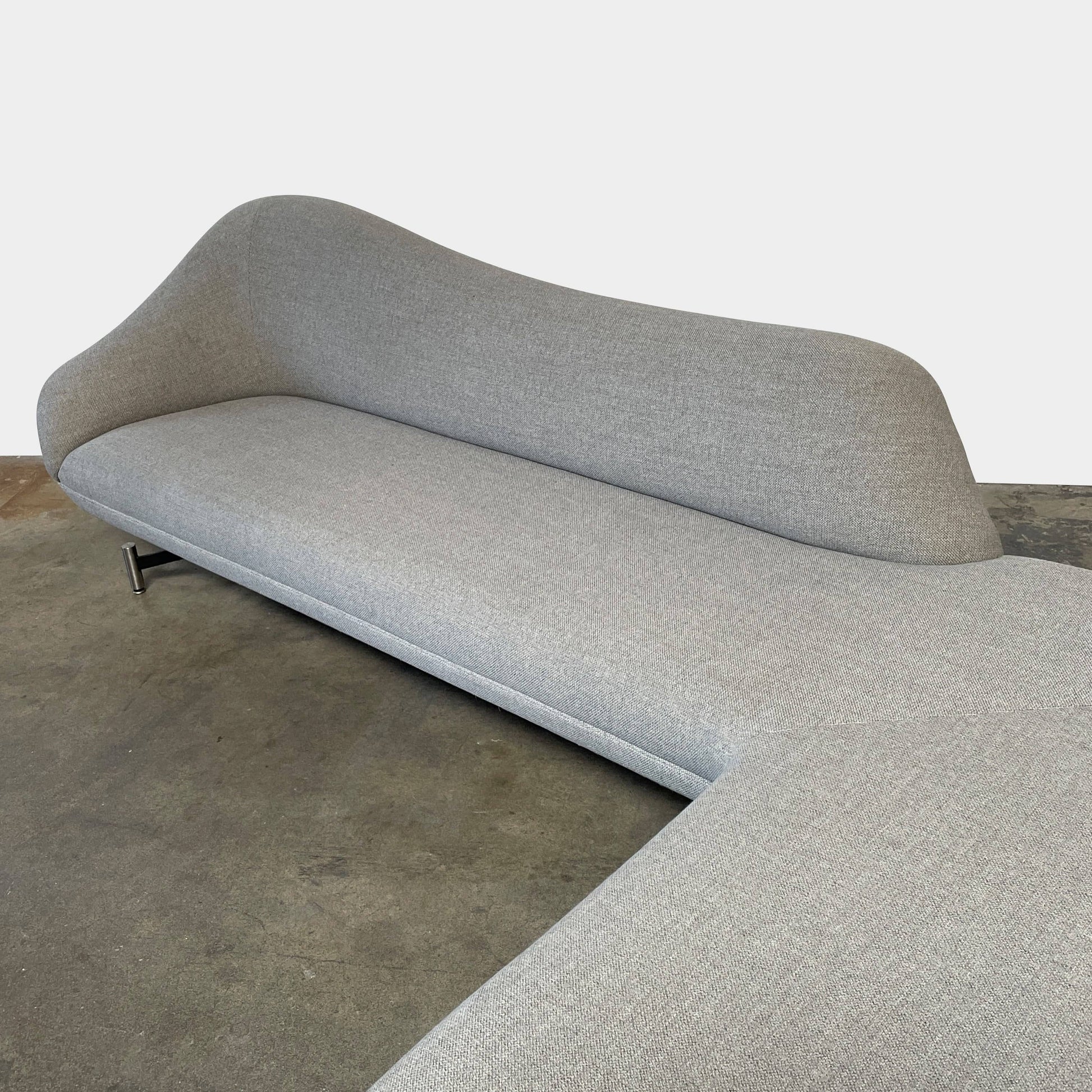 A Kagan Swan L-Shaped Sofa with legs on a white background.