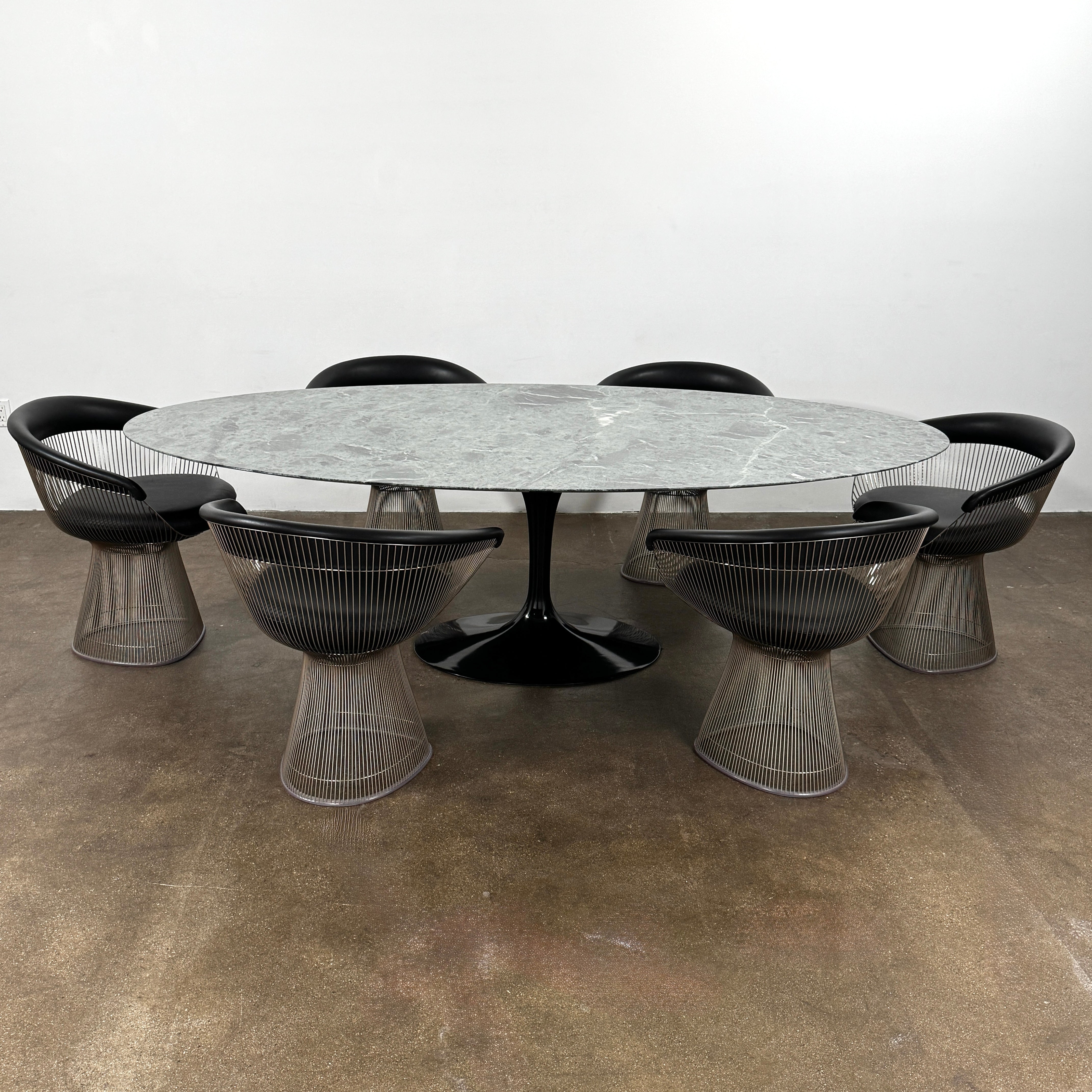 The Knoll Oval Verde Alpi Marble Saarinen Table features a gray marble top and a black pedestal base, inspired by the classic design, set against a plain white background.
