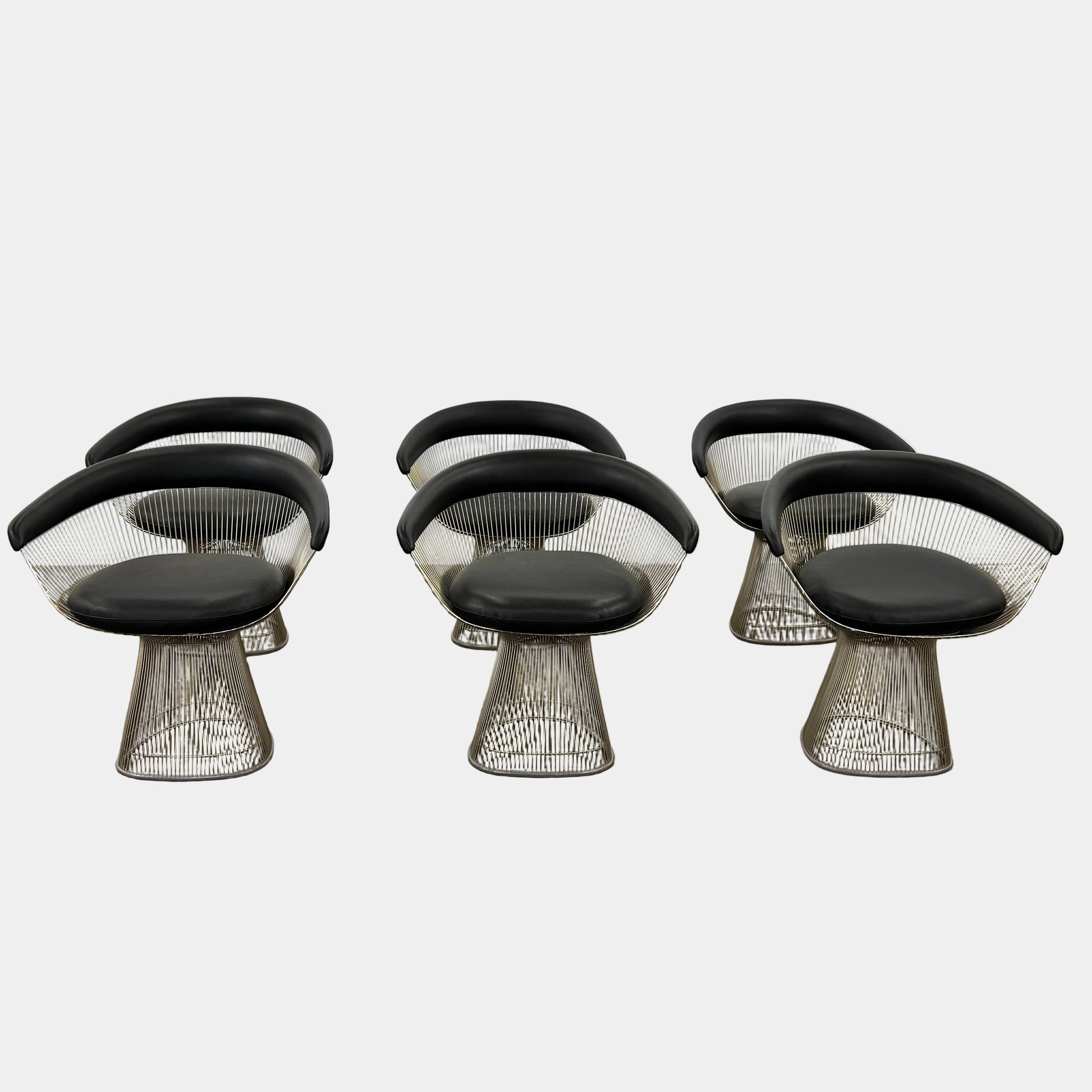 A set of six Knoll Platner Armchairs by Knoll, featuring black seats and backs with metal wire bases, inspired by modernist design, arranged in two rows against a plain white background.