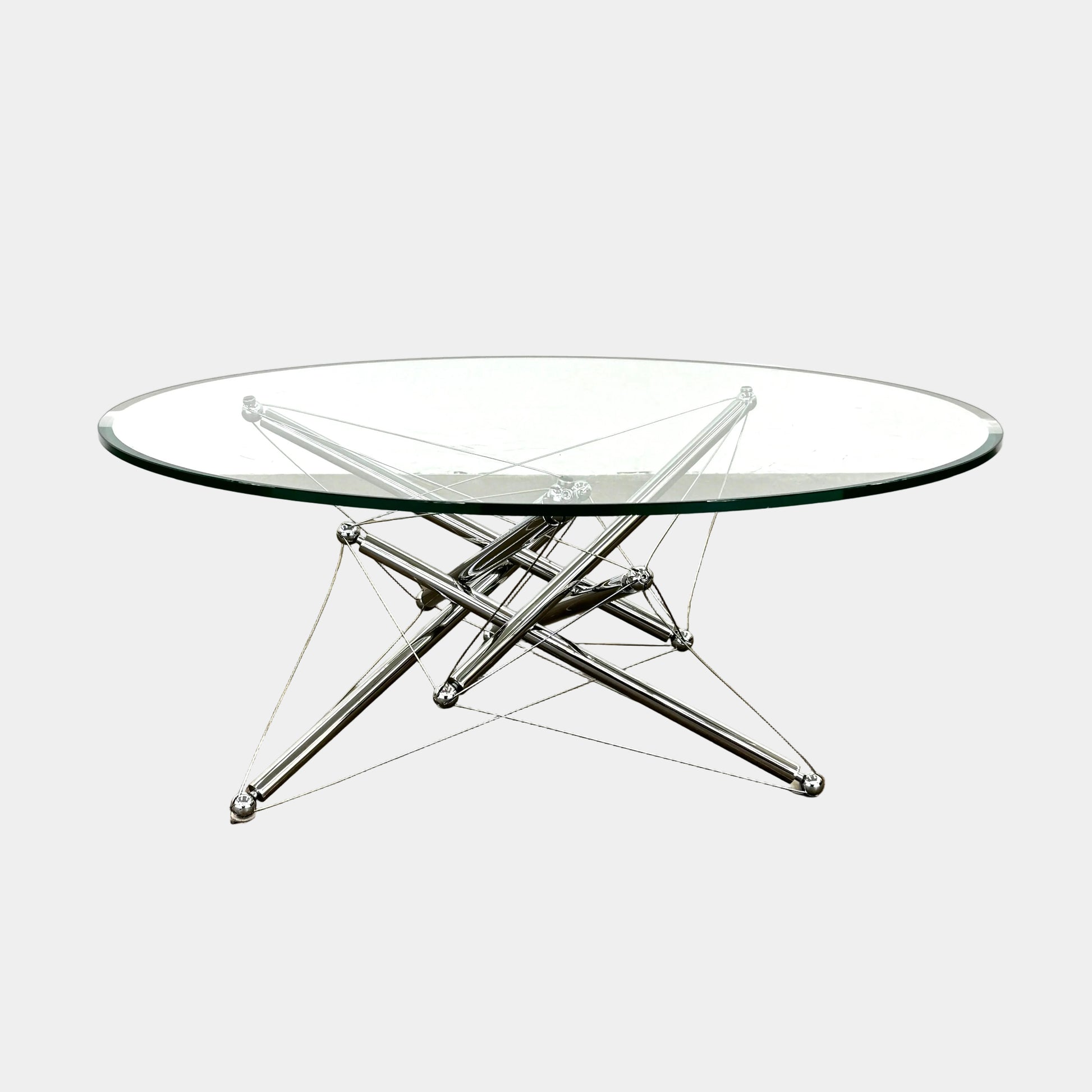 The Cassina "Tensegrity" 713 Cocktail Table features a round glass top and a geometric chrome metal base with tension cables, displayed on a plain white background.