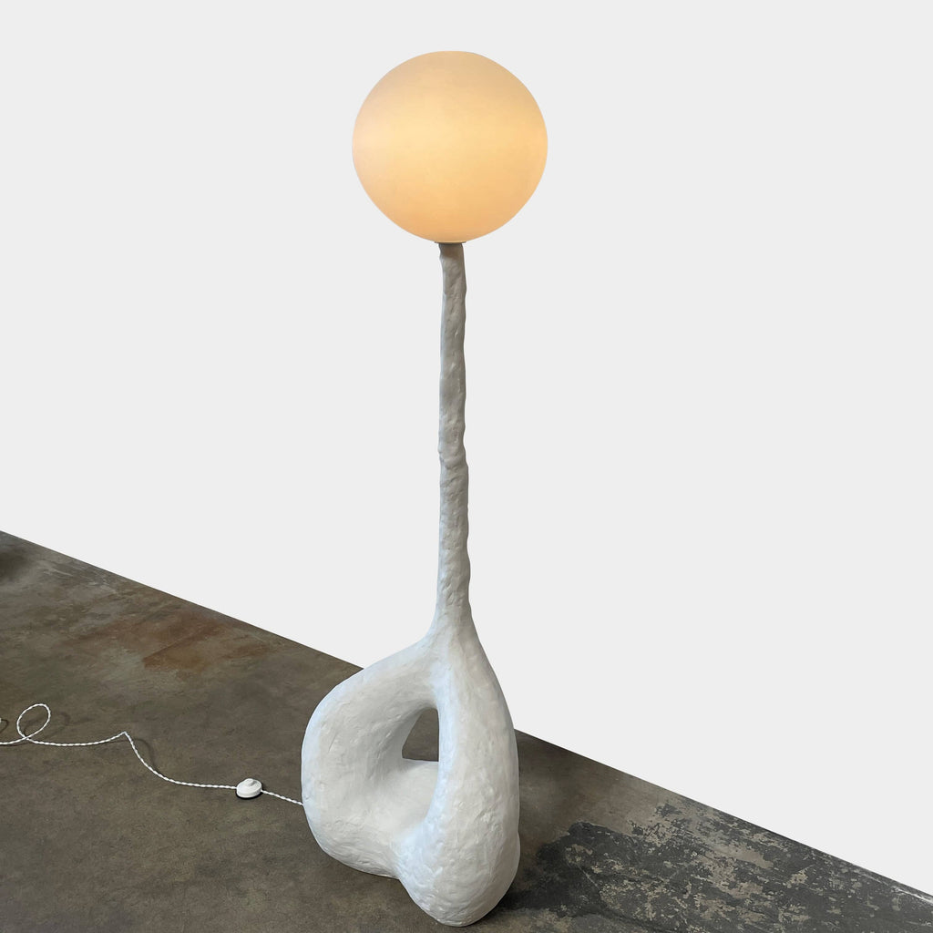 A Ralph Pucci Kukui Floor Light Sculpture with a ball on it.
