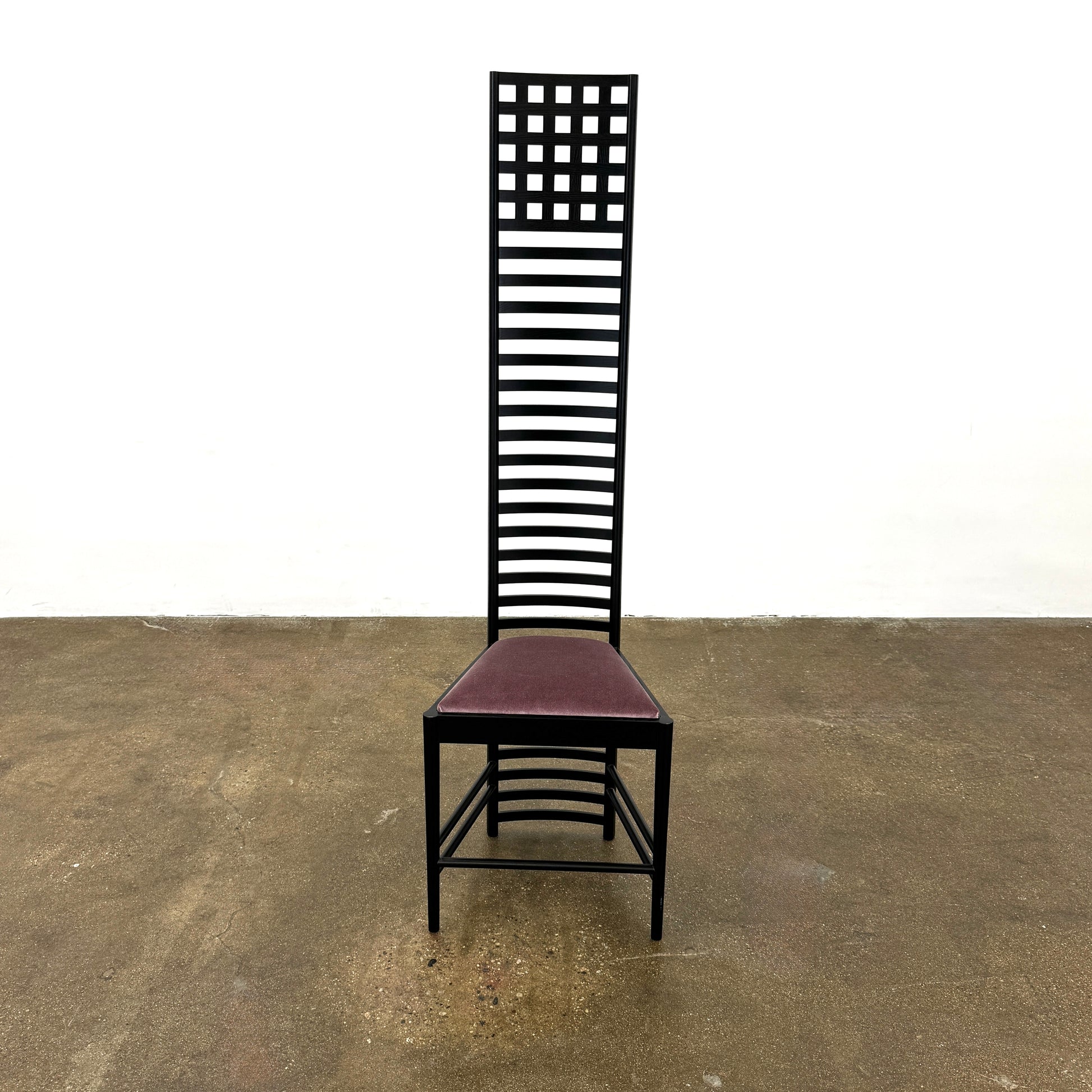 A pair of Cassina 292 Hill House Chairs by Charles R. Mackintosh, with black slatted frames—one featuring a burgundy seat cushion, the other dark green—showcasing Cassina's modernist design against a plain white background.